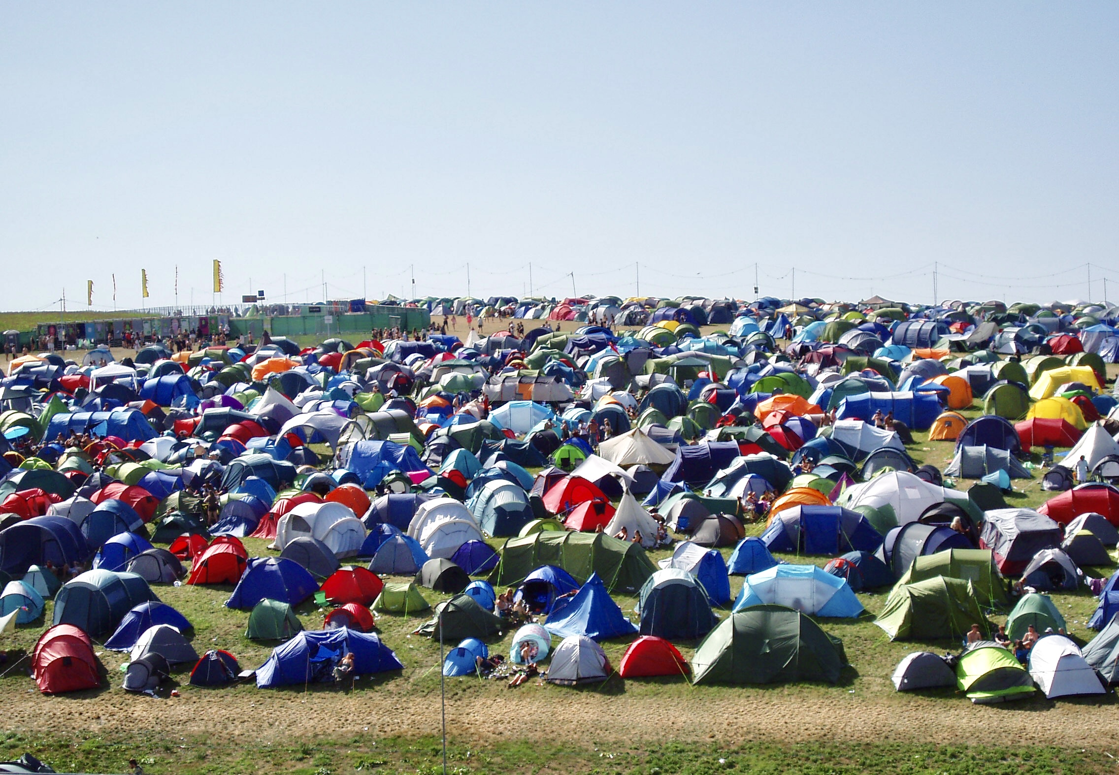 A field full of tents at a music festival on a bright sunny day.