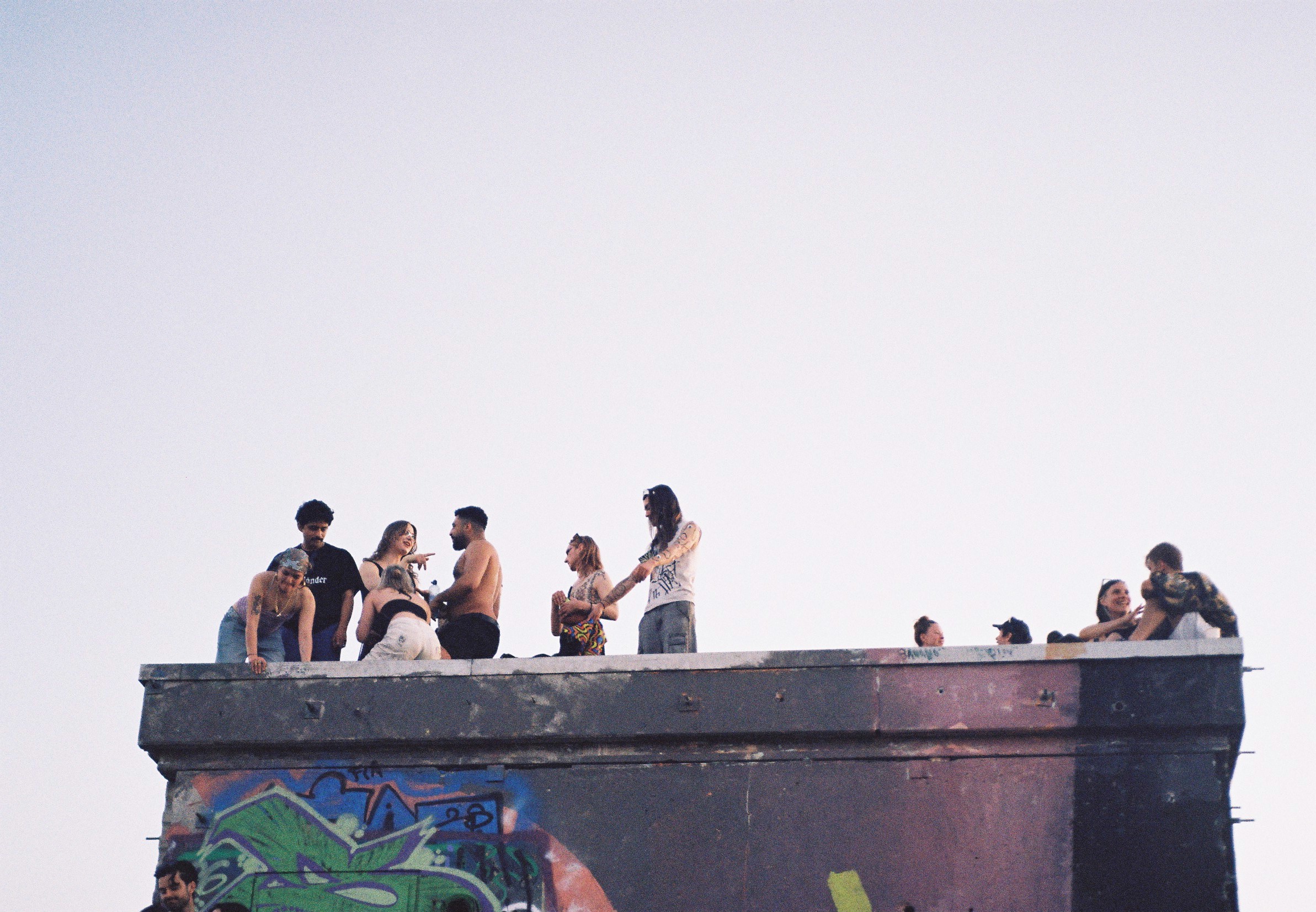 Een groep mensen op een betonnen gebouw, open lucht op een zomerdag, gefotografeerd door Mara Silverio.