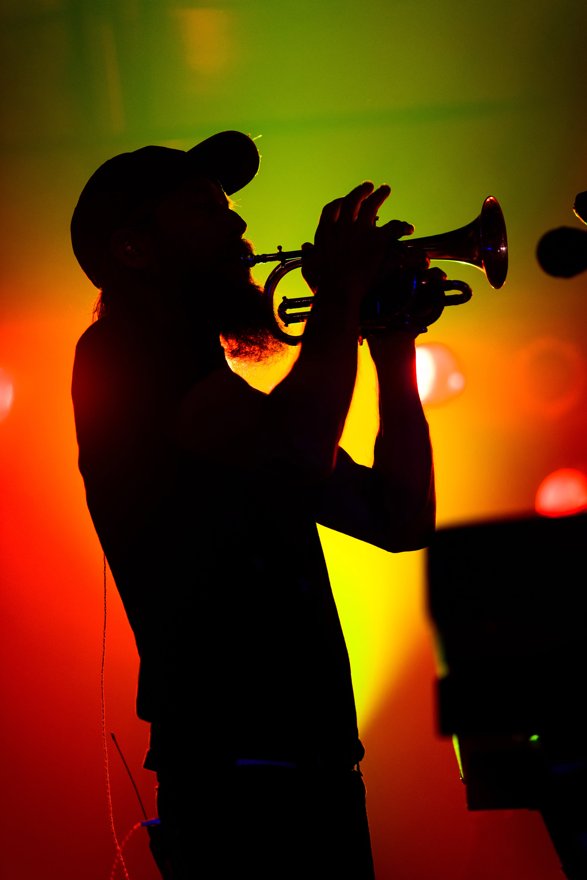 Modest mouse trumpet player on stage with light in background, photo by James Joiner.