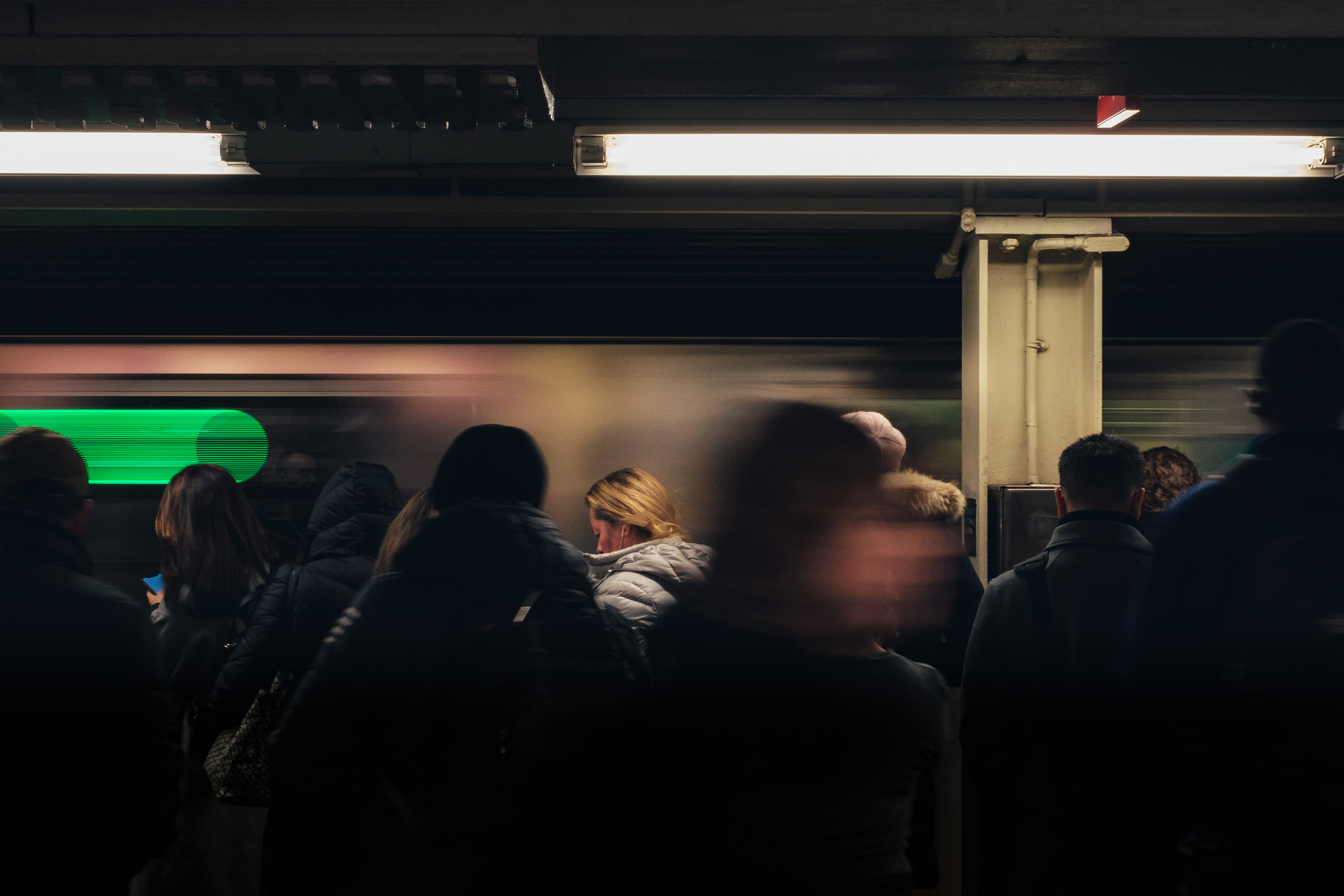 Mensen wachten op de metro van New York City met een voorbijrijdende metro, gefotografeerd door Manuel Pena.