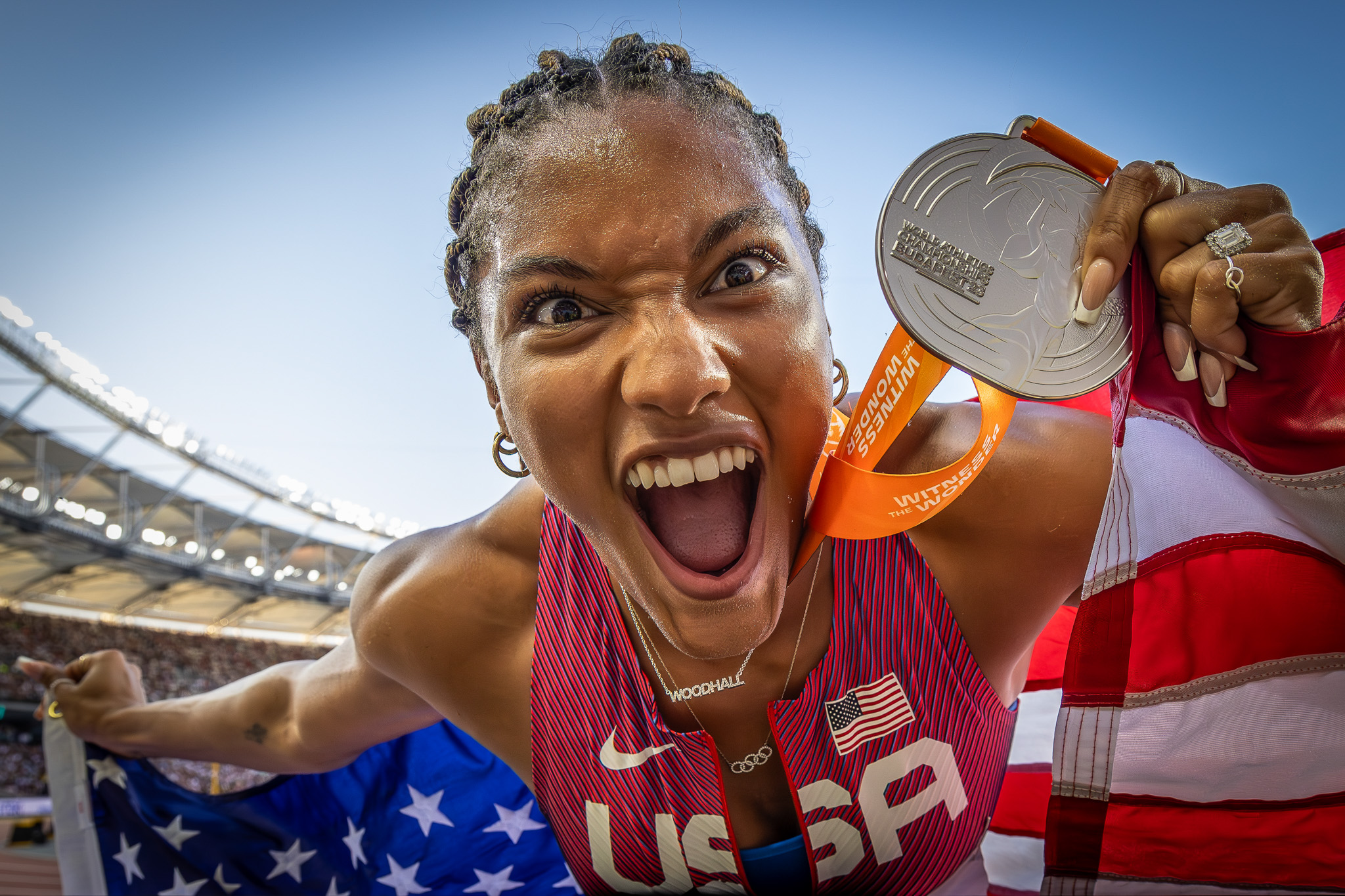 An athlete celebrates joyfully with their silver medal close to the camera. By Alex Kohring.