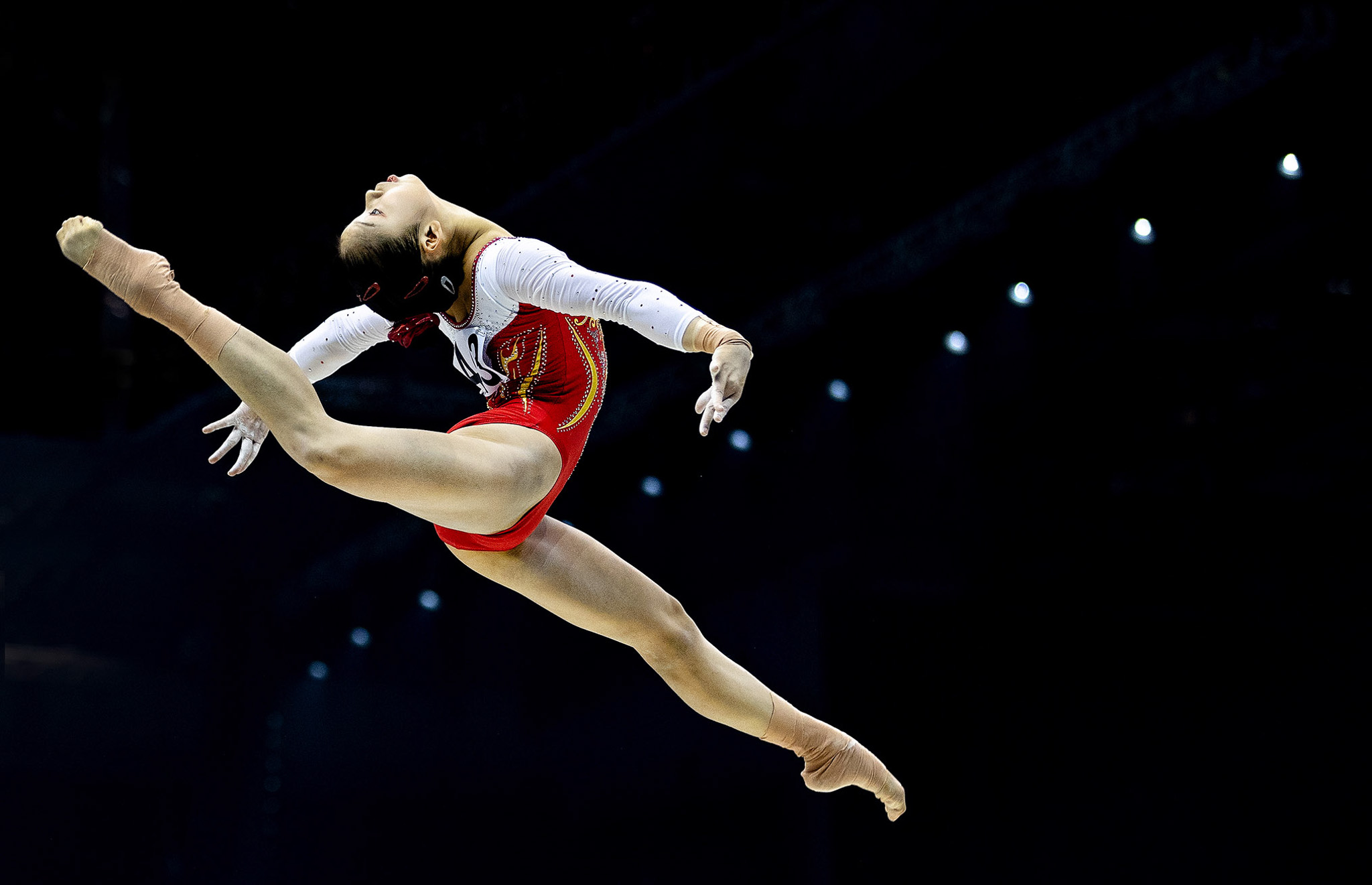 An elegant gymnast mid-jump and dance. By Iris van den Broek.