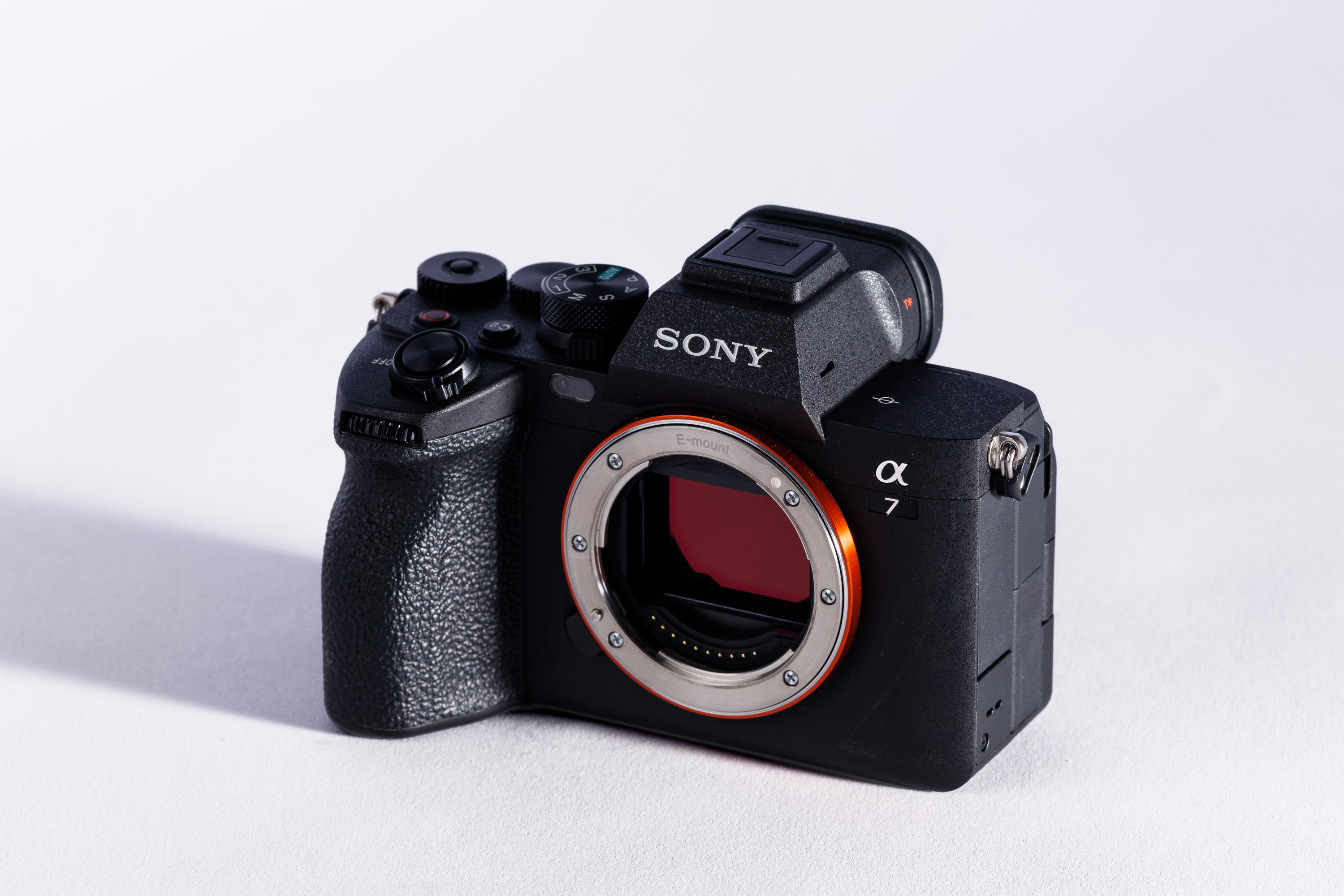 A used Sony A7 IV body on a white background, with a shadow to the left. 