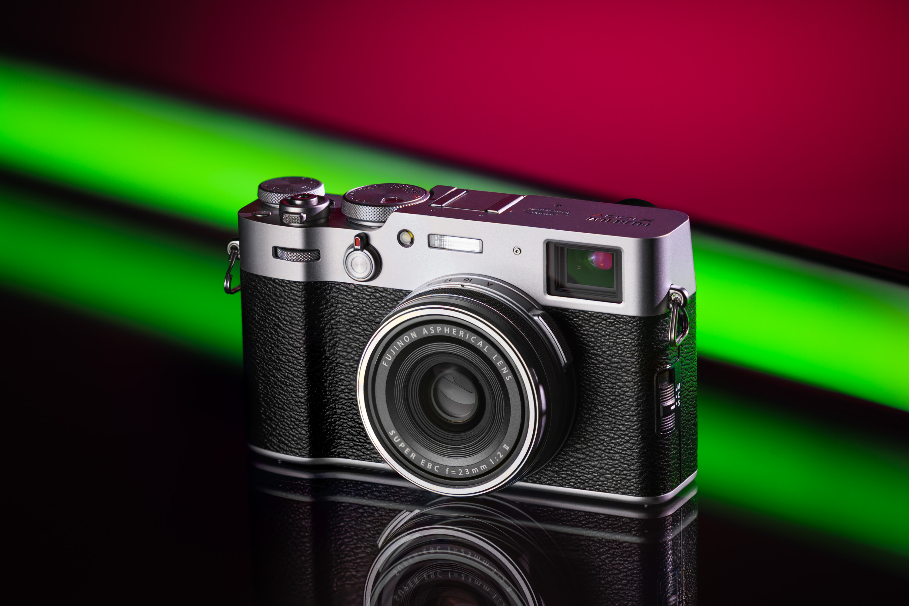 Tweedehands Fujifilm X100V op een felgroene en kastanjebruine achtergrond