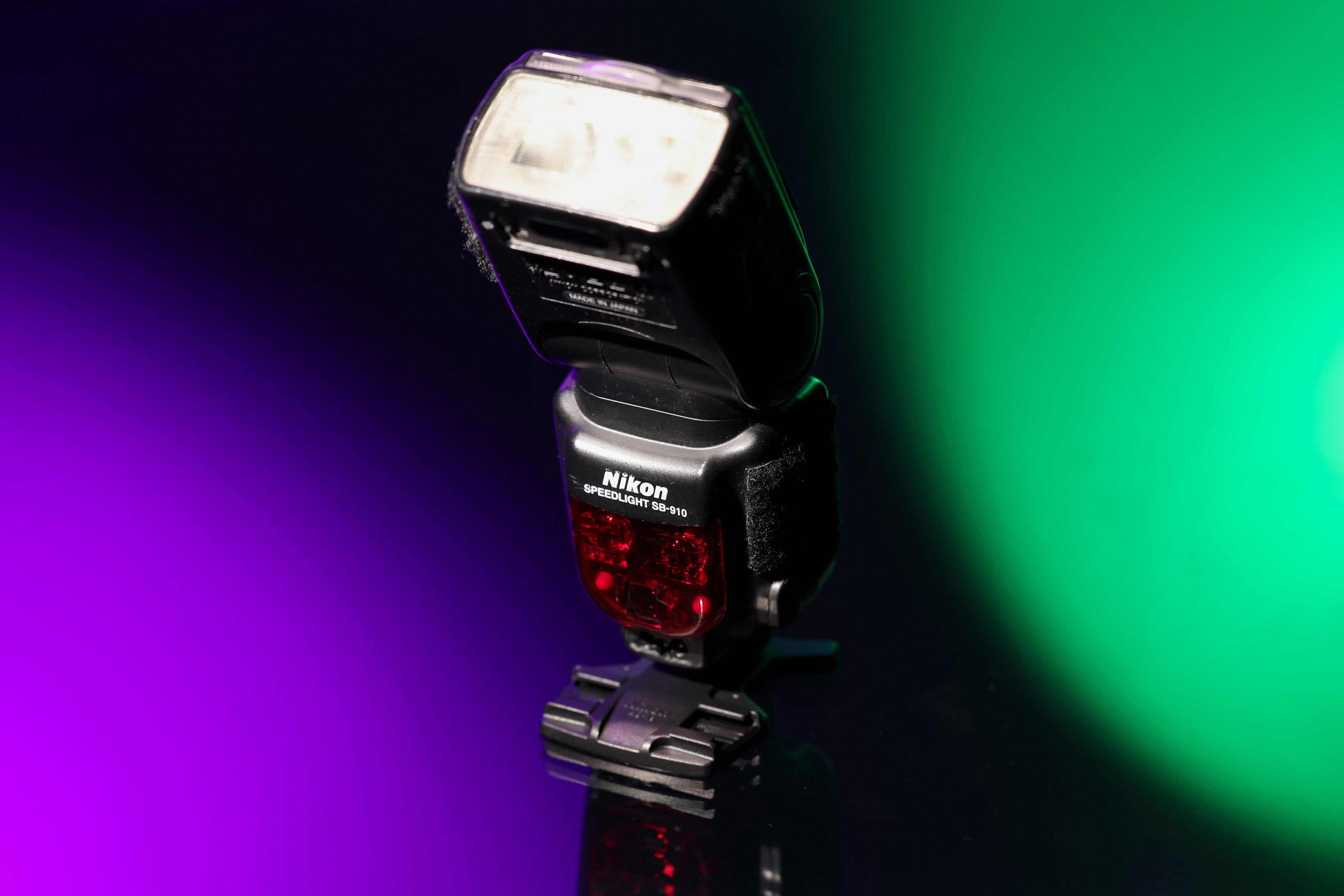 Nikon SB-910 Speedlight against a purple, black and green background.
