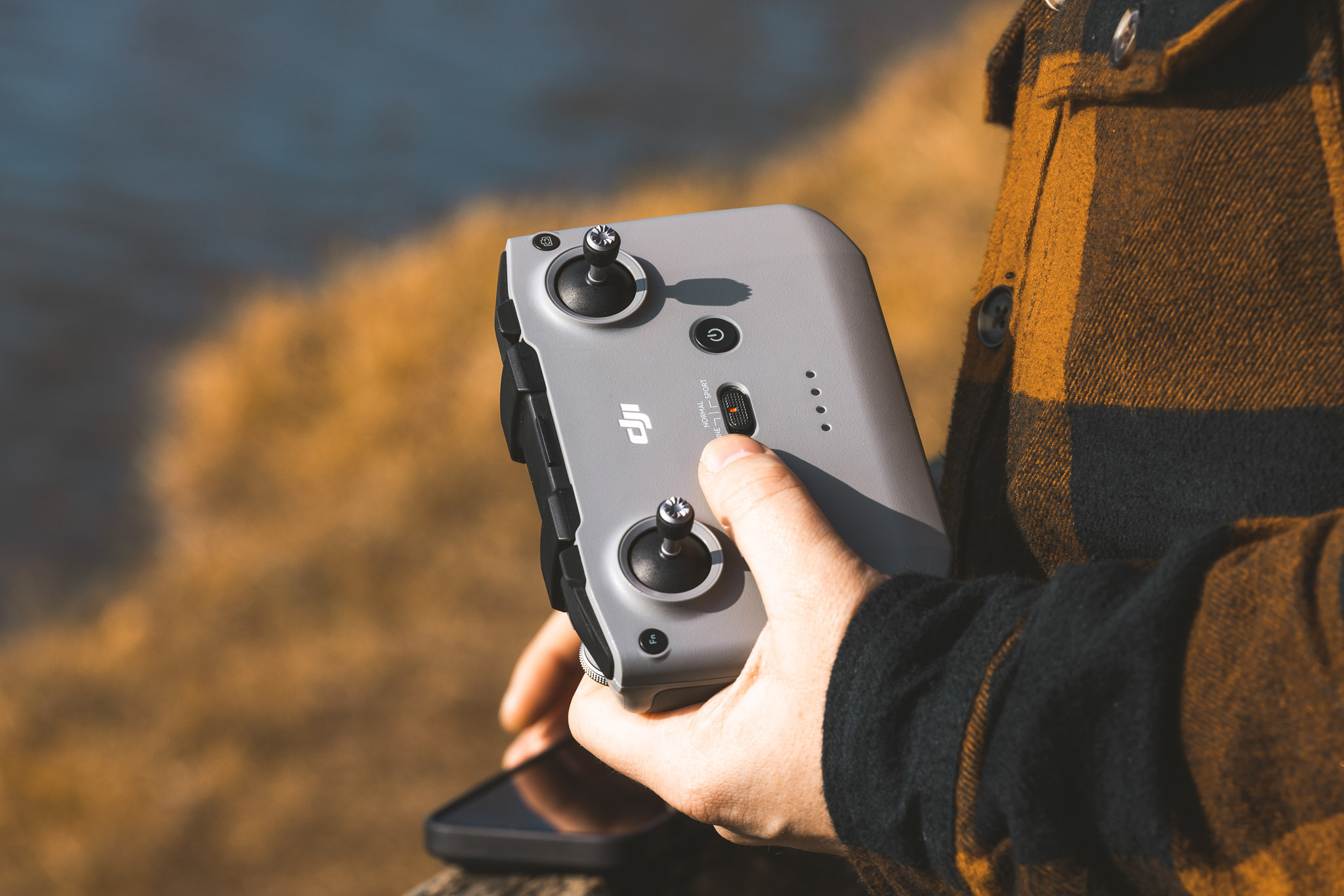 Person holding a DJI RC‑N1 drone controller outdoors, showing the joysticks and flight mode switch.