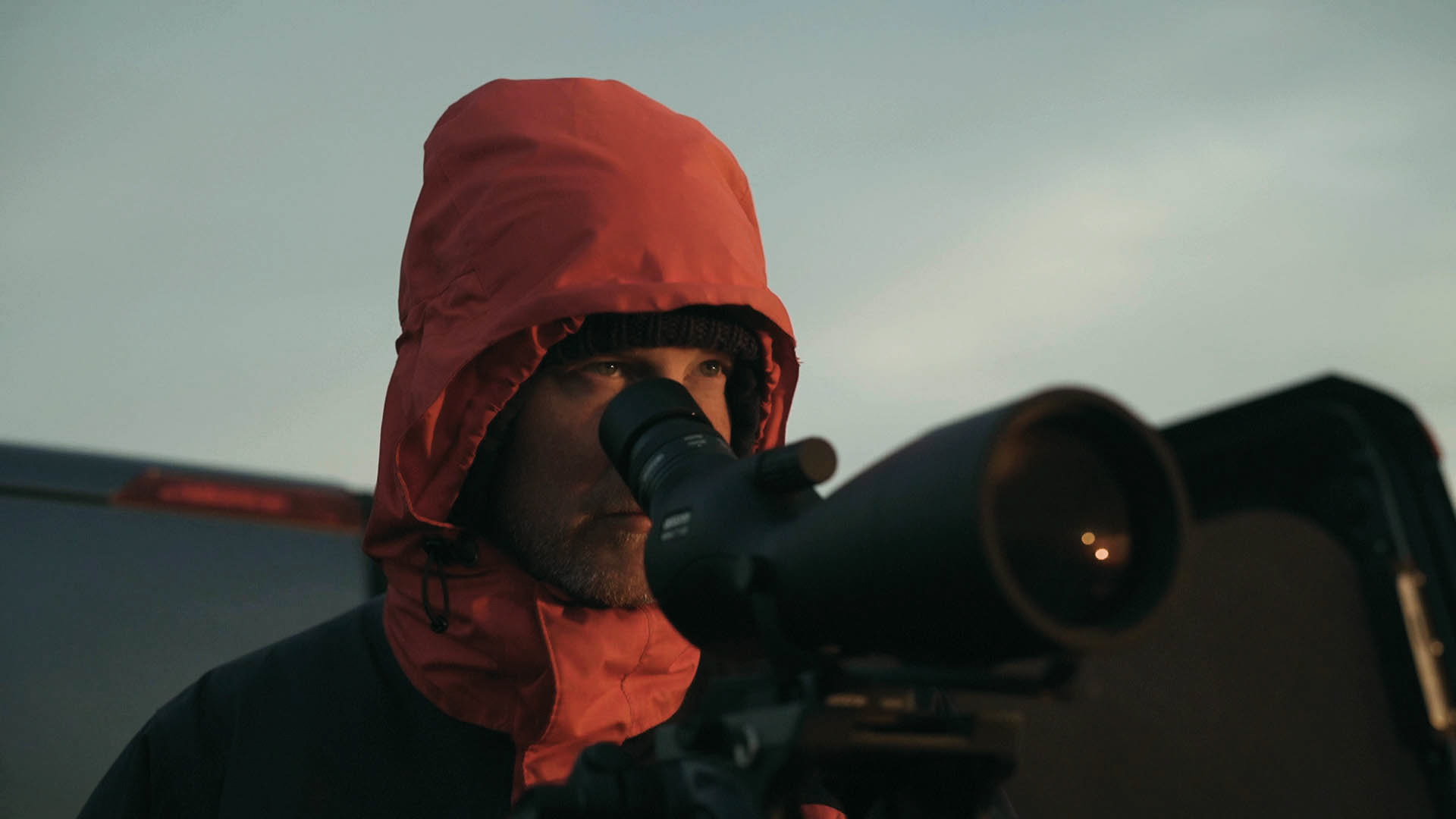 Een persoon in een rode waterdichte jas tuurt boven een telescoop, een opname uit de korte film Truluck van Matt Cannon en Jake Smallwood.