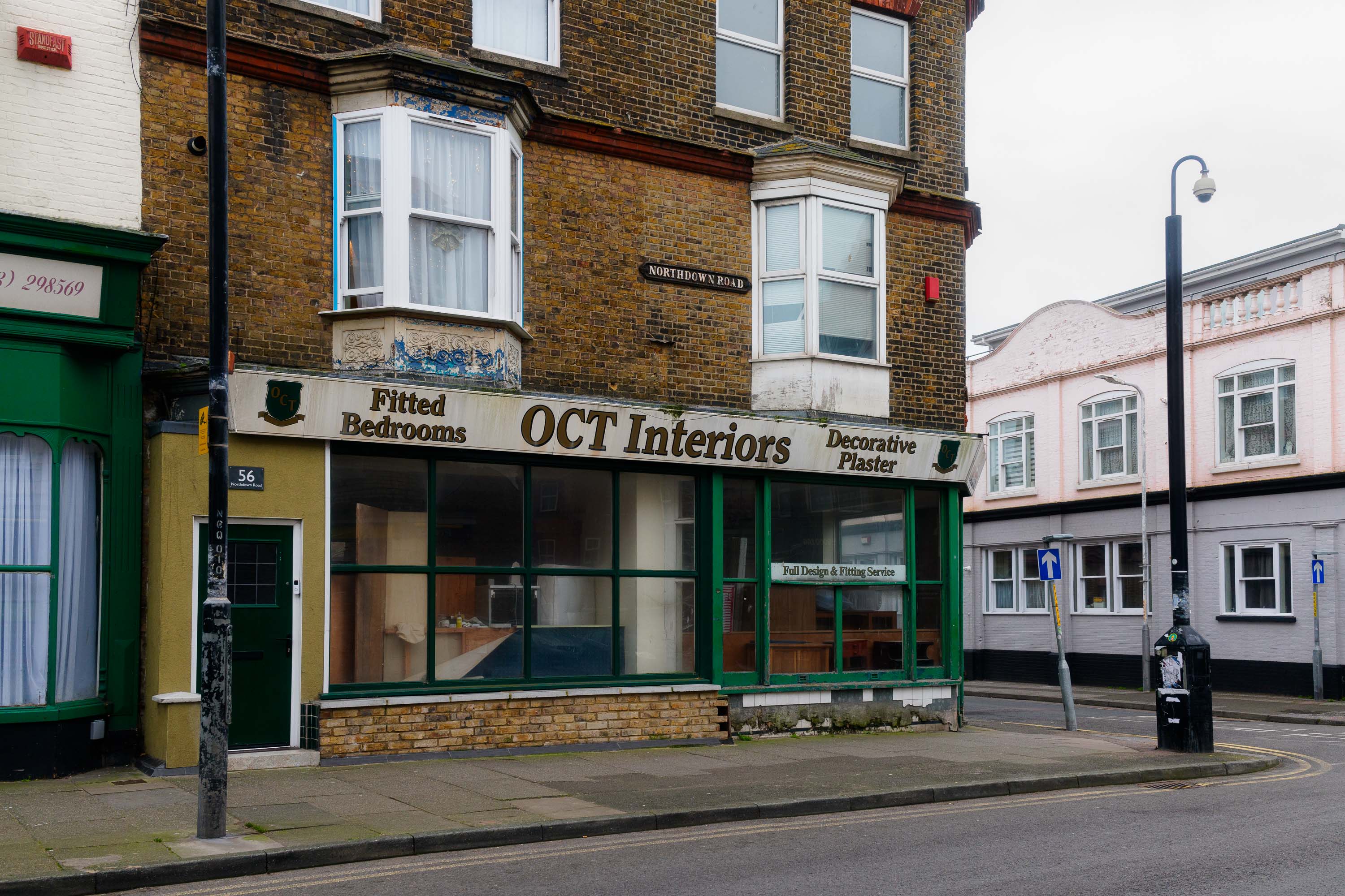 Ein Möbelgeschäft mit Vintage-Schild „OCT Interiors“ in einem Backsteingebäude, fotografiert in einer ruhigen Straße mit Erkerfenstern bei gedämpftem, bedecktem Licht. Aufgenommen von Connor Redmond mit einer Sony RX1R III.