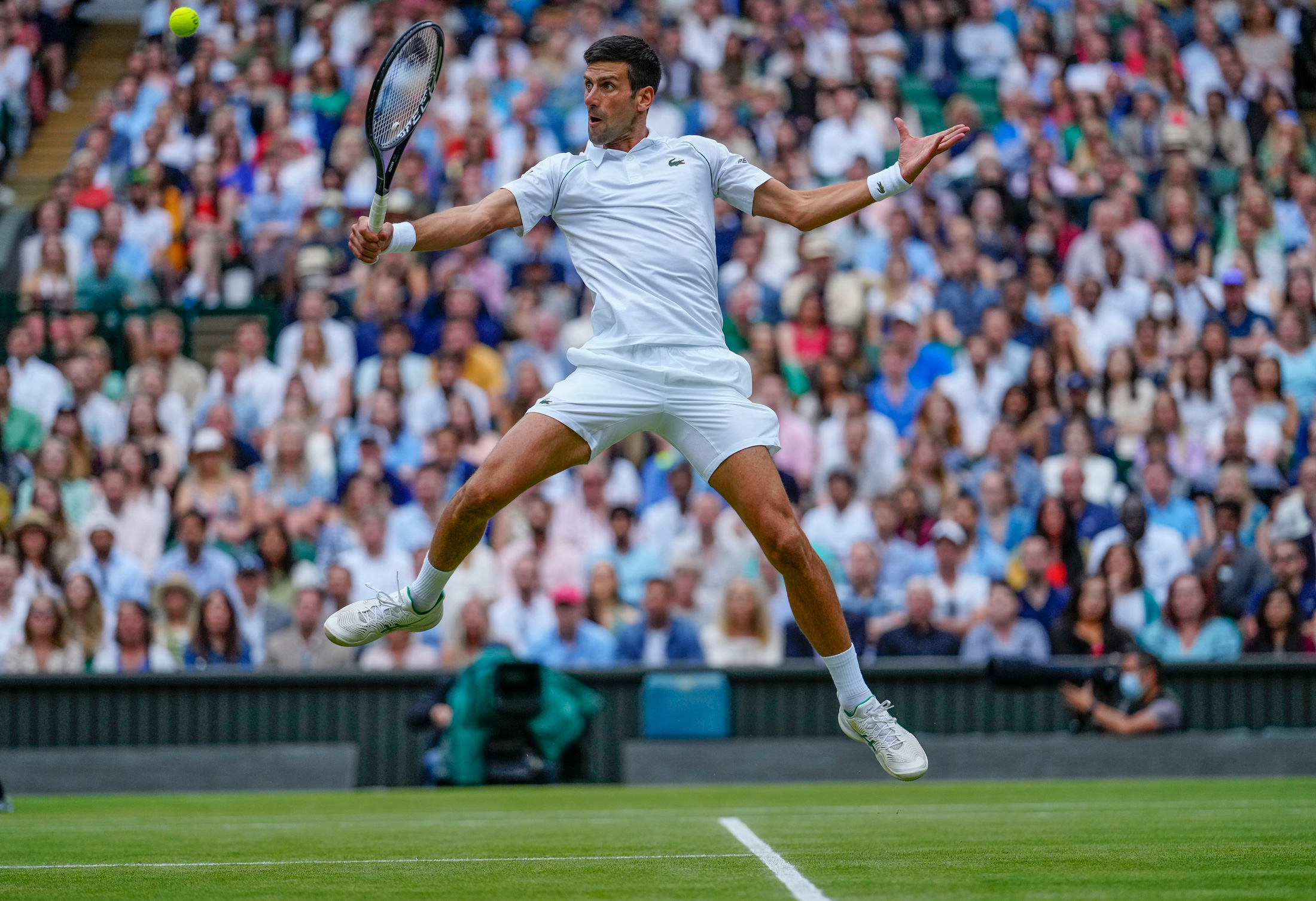 Photo of a tennis player returning a shot in mid-air.
