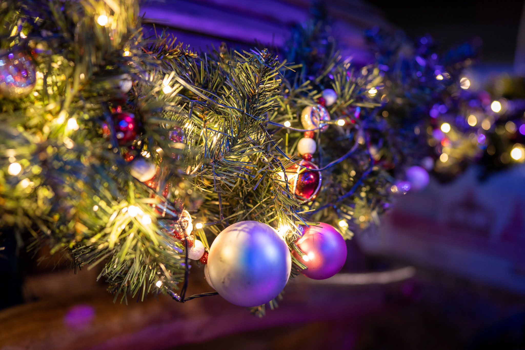 Nahaufnahme von Tannenzweigen mit Lichterkette und Christbaumkugeln, aufgenommen mit einer Sony Alpha A7C und einem Sony FE 24mm f/1.4 GM