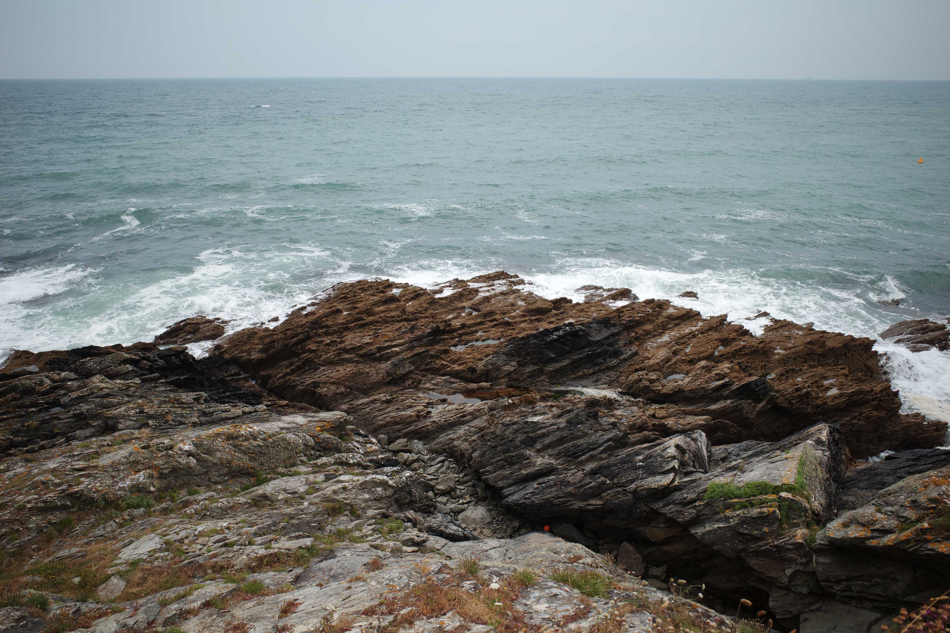 Rocky shore with waves lightly crashing over it in Cornwall