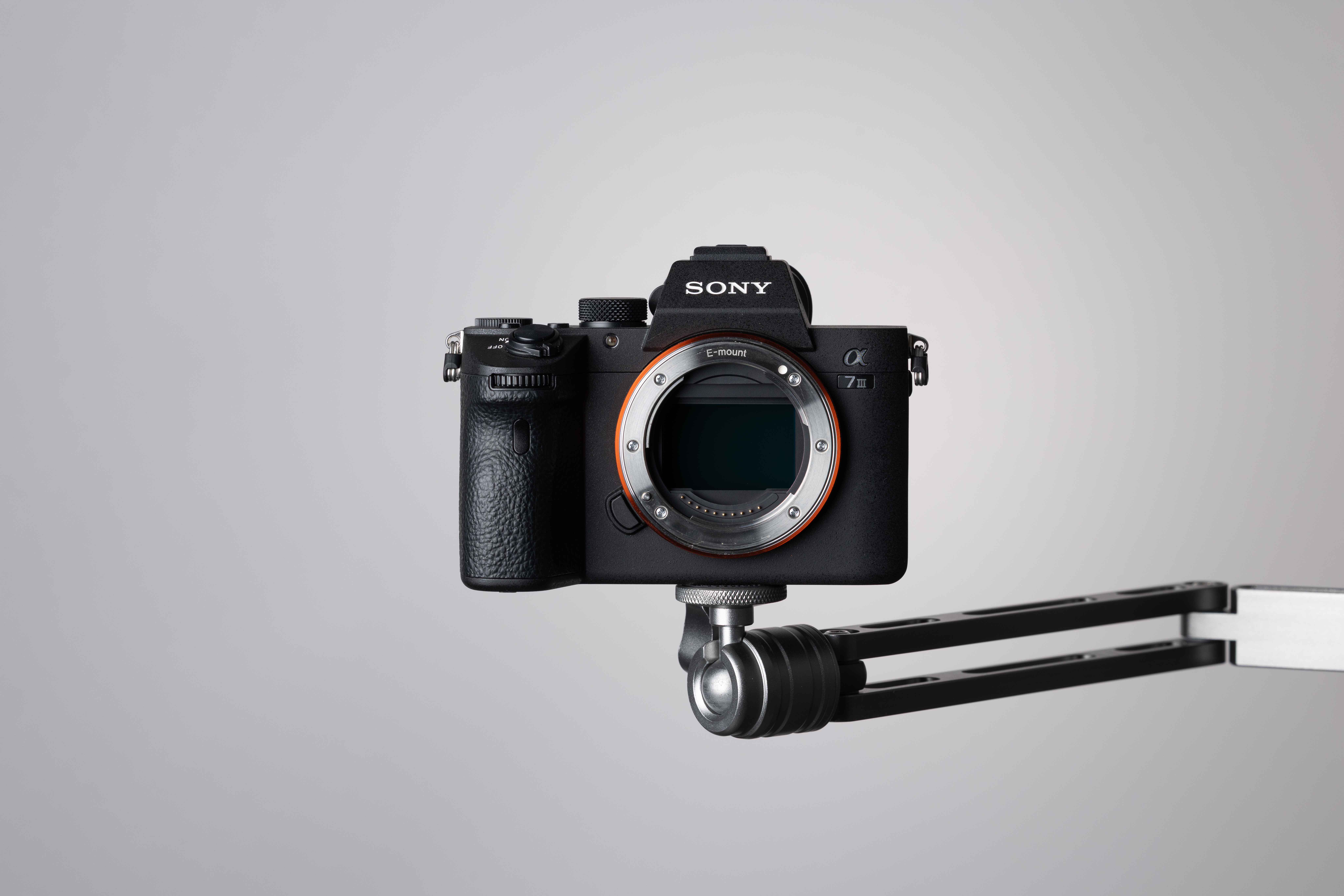 A used Sony A7 III on top of a metal mount on a grey background.