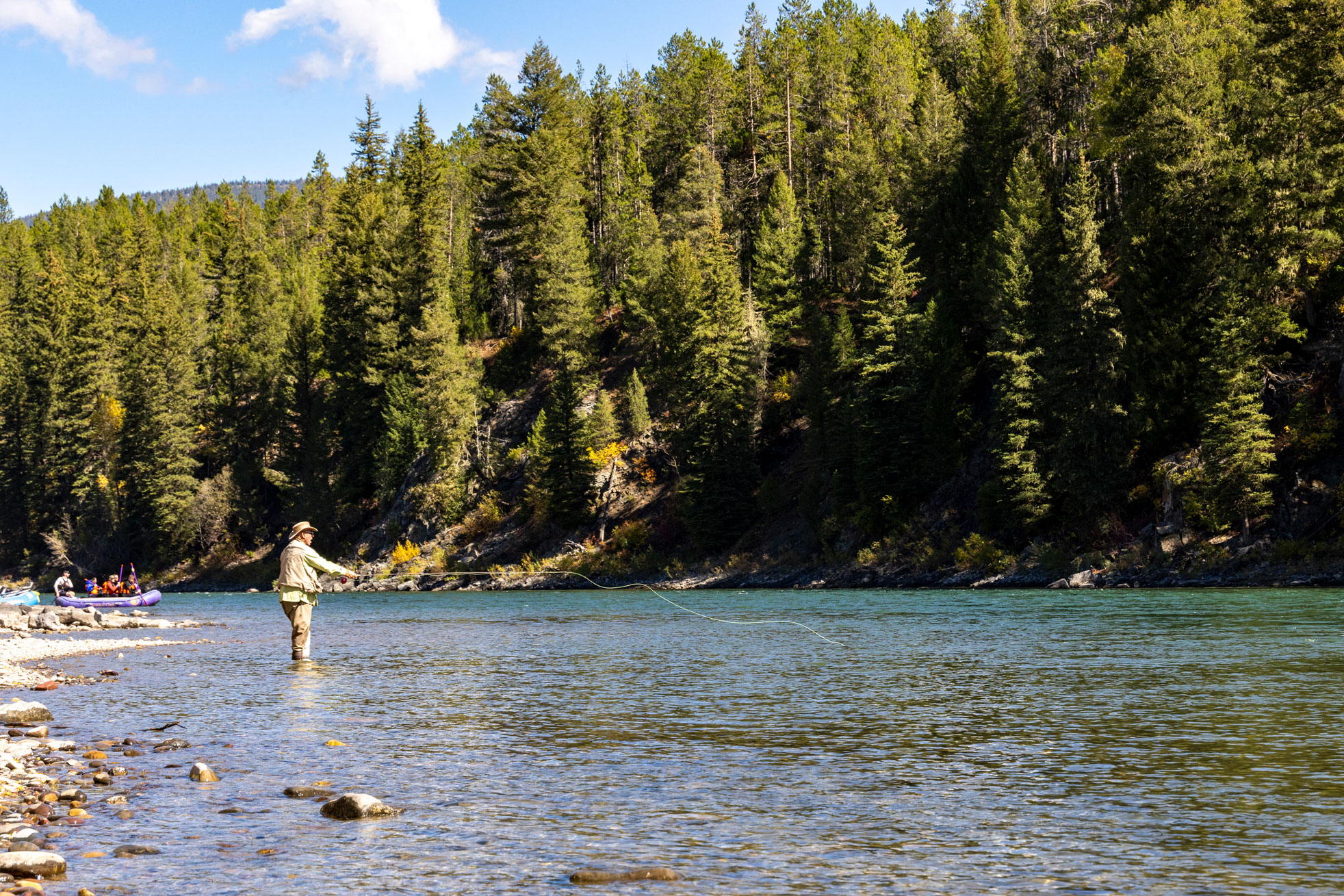 Fliegenfischer beim Auswerfen der Angel an einem Fluss in Wyoming. Im Hintergrund Bäume. Aufgenommen von Kristi Townsend mit einer Canon EOS R7.