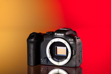 Cámara Canon EOS R7 de segunda mano sobre un fondo amarillo y rojo