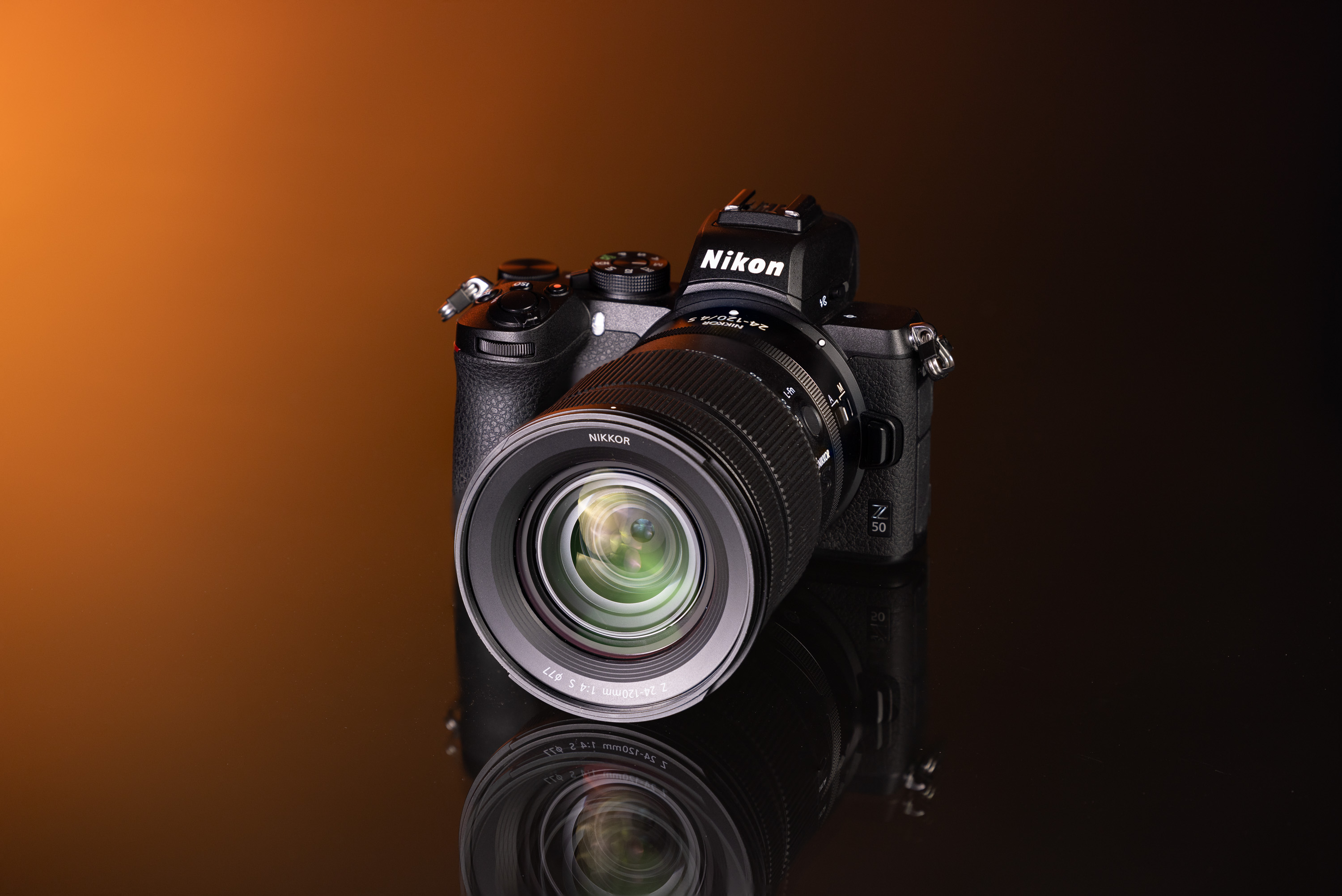 Tweedehands Nikon Z50 en Nikon Nikkor Z 24-120mm f/4 S op een oranje en zwarte achtergrond.