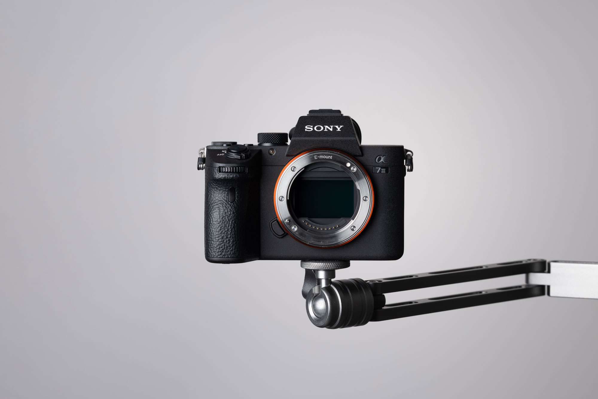 A used Sony A7 III on top of a metal mount on a grey background.