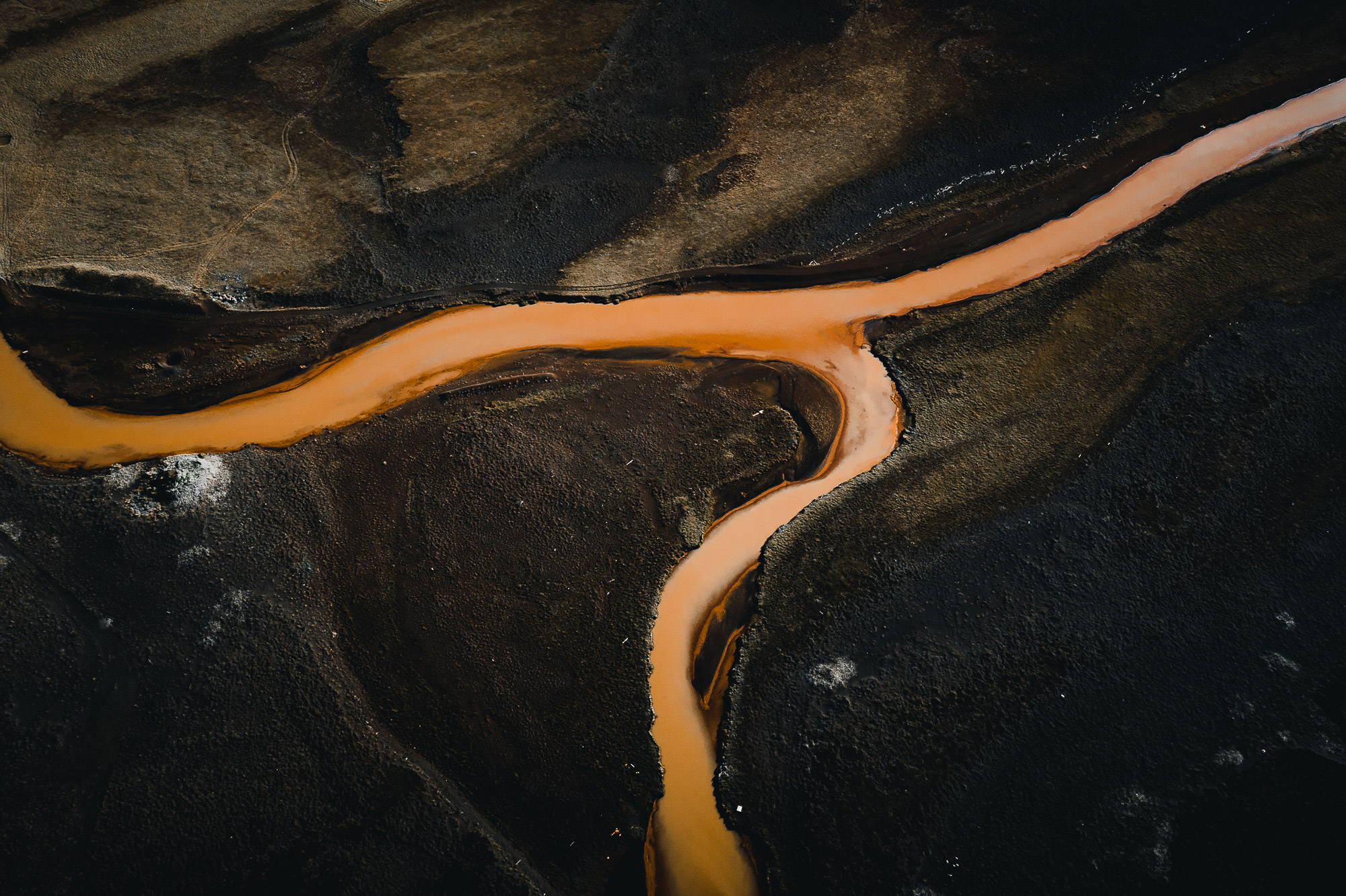 Aerial drone bird’s-eye photo of an orange river running through a valley with green fields on either side in Iceland, shot by Paul Watson with a DJI Mavic 2 Pro
