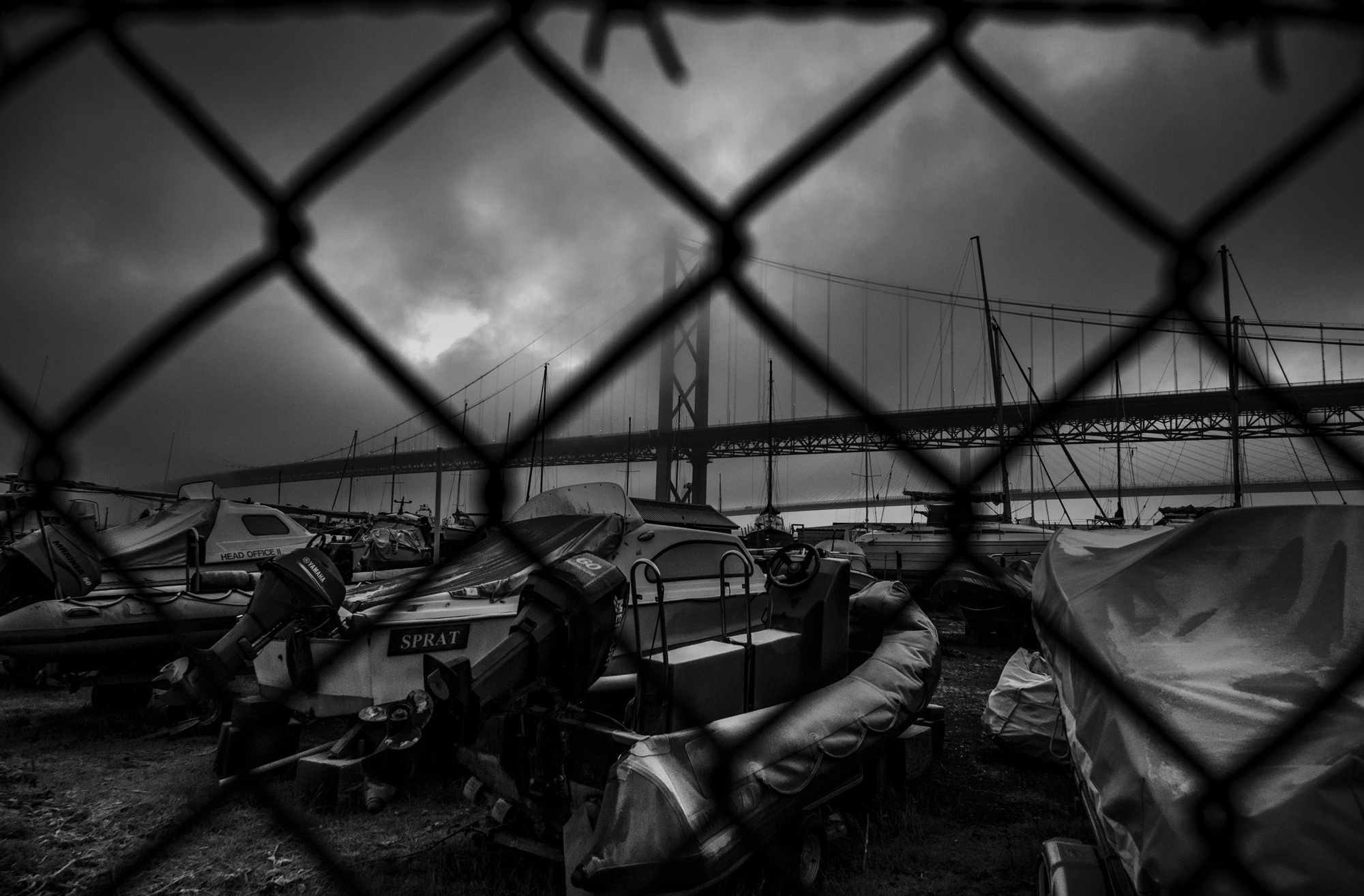 A black and white image of a bridge behind a fence, shot by Scott Jessiman with a Nikon Z6 II