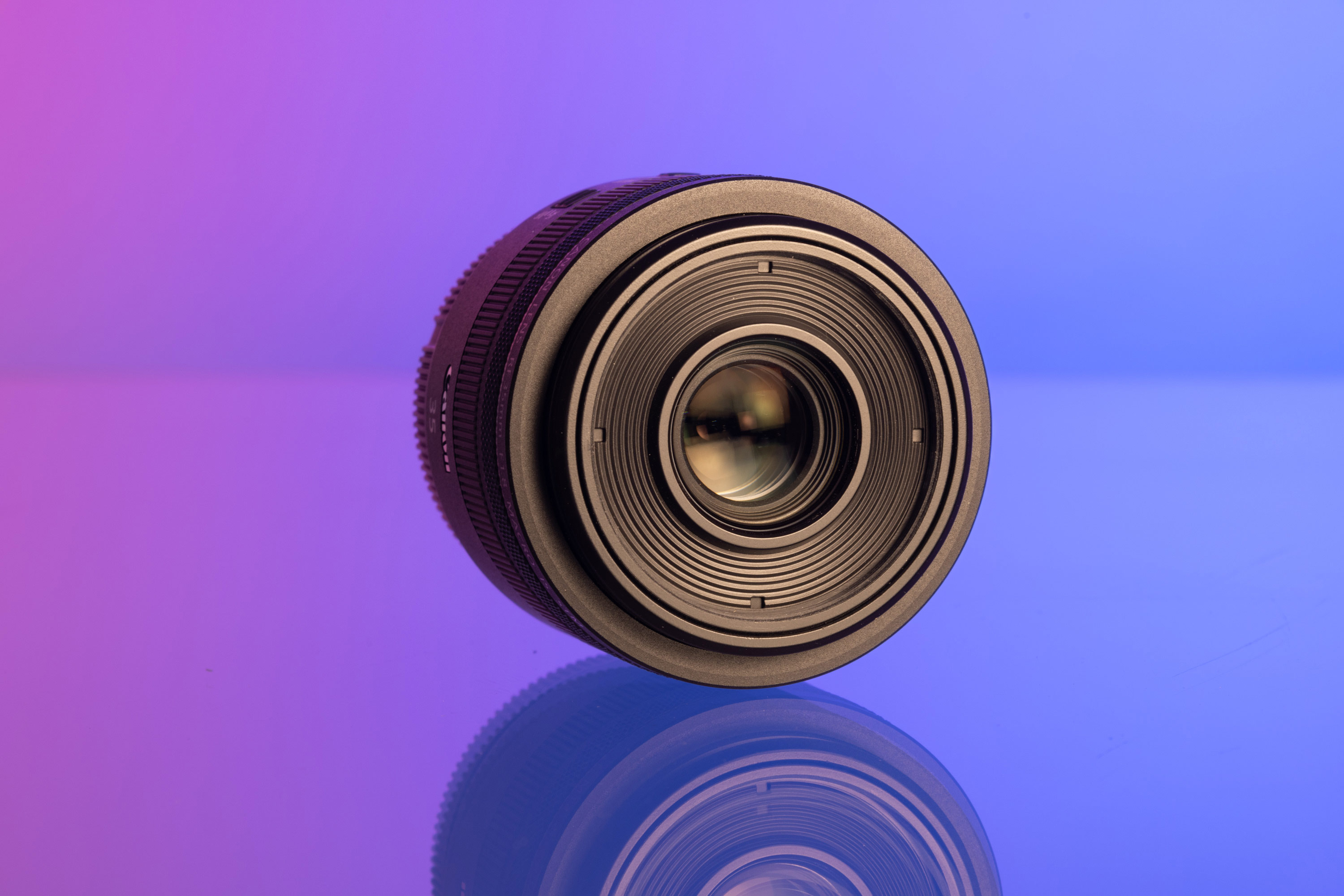 Canon RF 35mm f/1.8 IS STM Macro lens on a purple and blue background