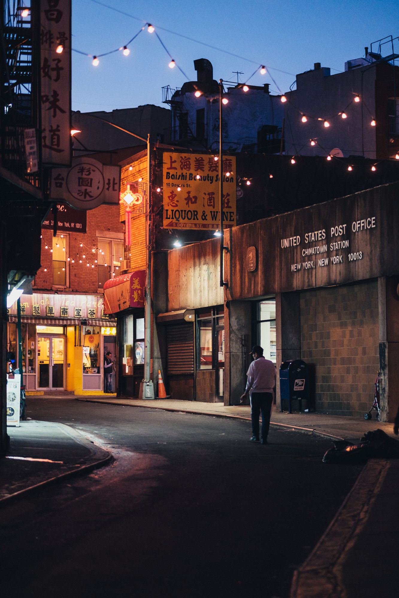 Persoon loopt 's nachts door de New York City Chinatown straat met lichtstraal, gefotografeerd door Manuel Pena.