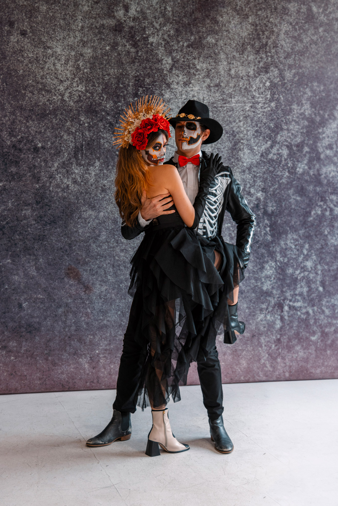 Day of the Dead cosplayers pose against a grey backdrop.