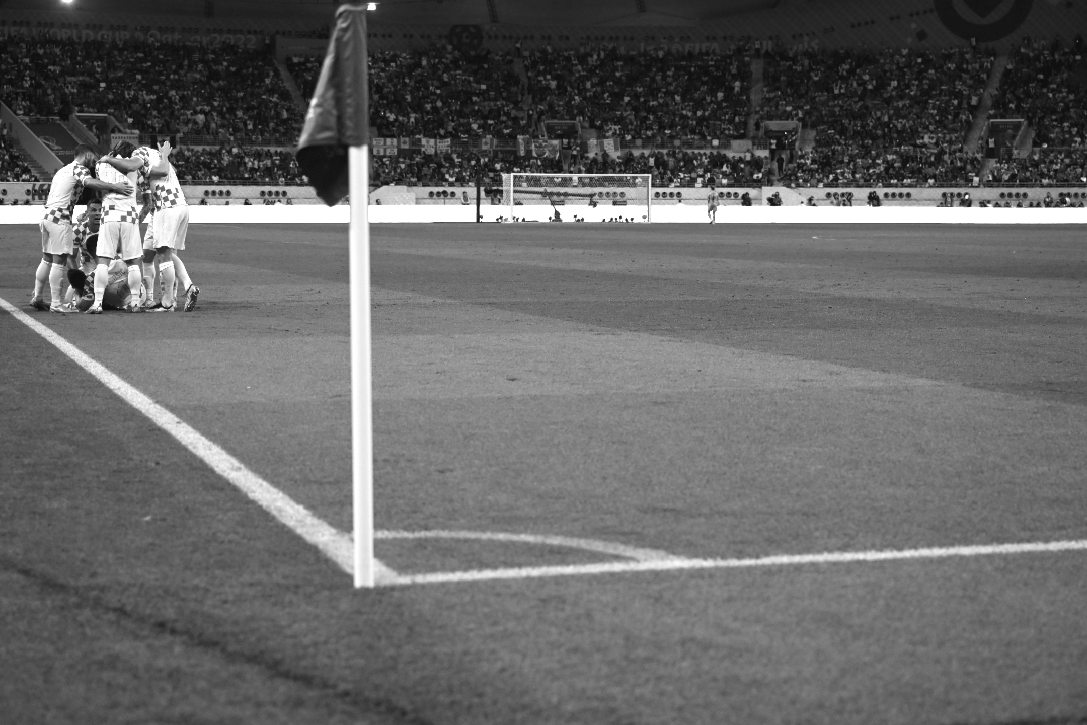 Ein Schwarz-Weiß-Foto von Kroatien, das während des 4:1-Sieges gegen Kanada bei der Fußball-Weltmeisterschaft 2022 feiert. Die Eckfahne ist im Vordergrund, aufgenommen von Ryu Voelkel mit einer Nikon Z9.