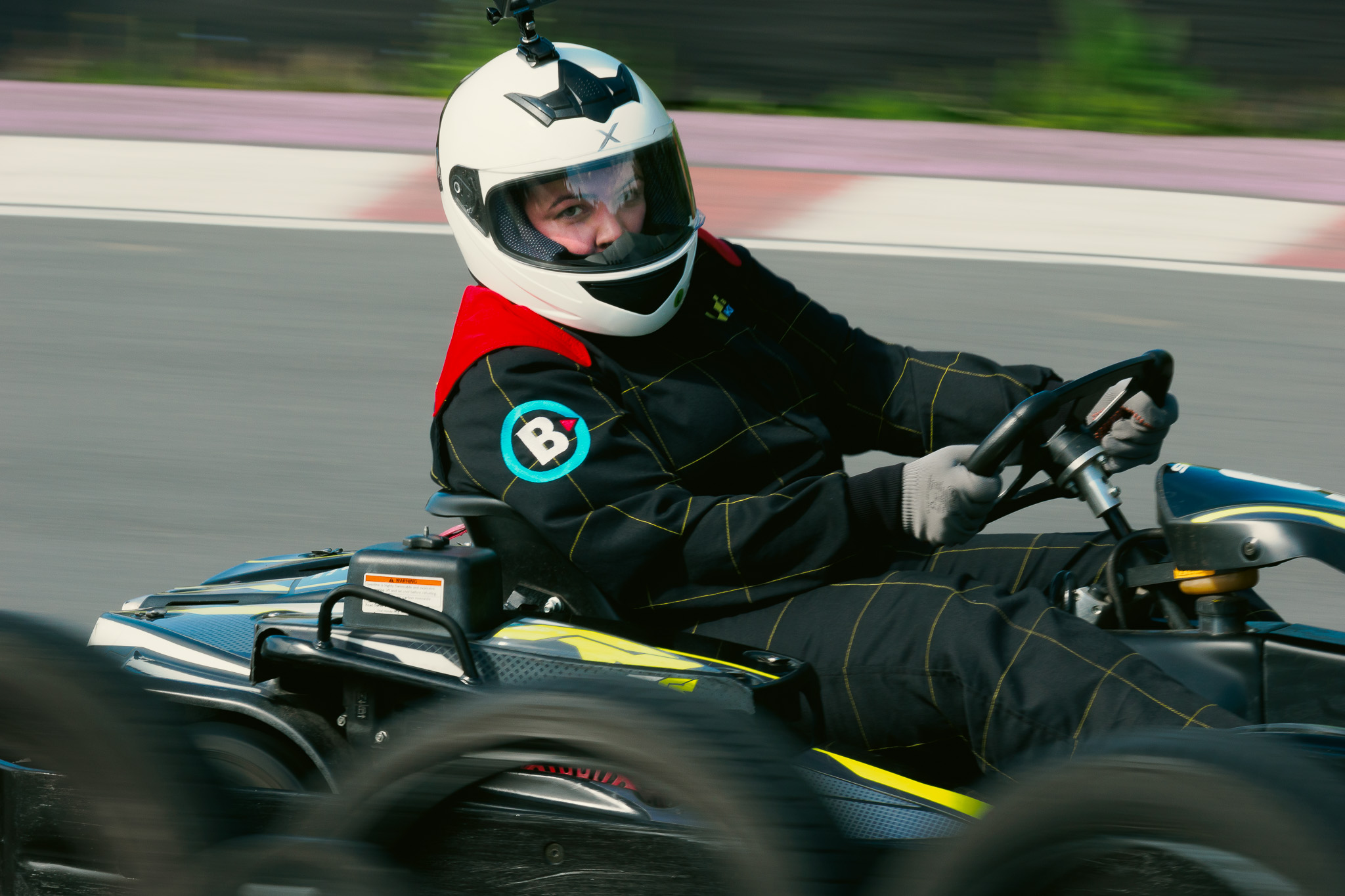 Amy Moore in een gokart op snelheid terwijl ze recht in de lens kijkt, foto door Connor Redmond met de OM System OM-1.