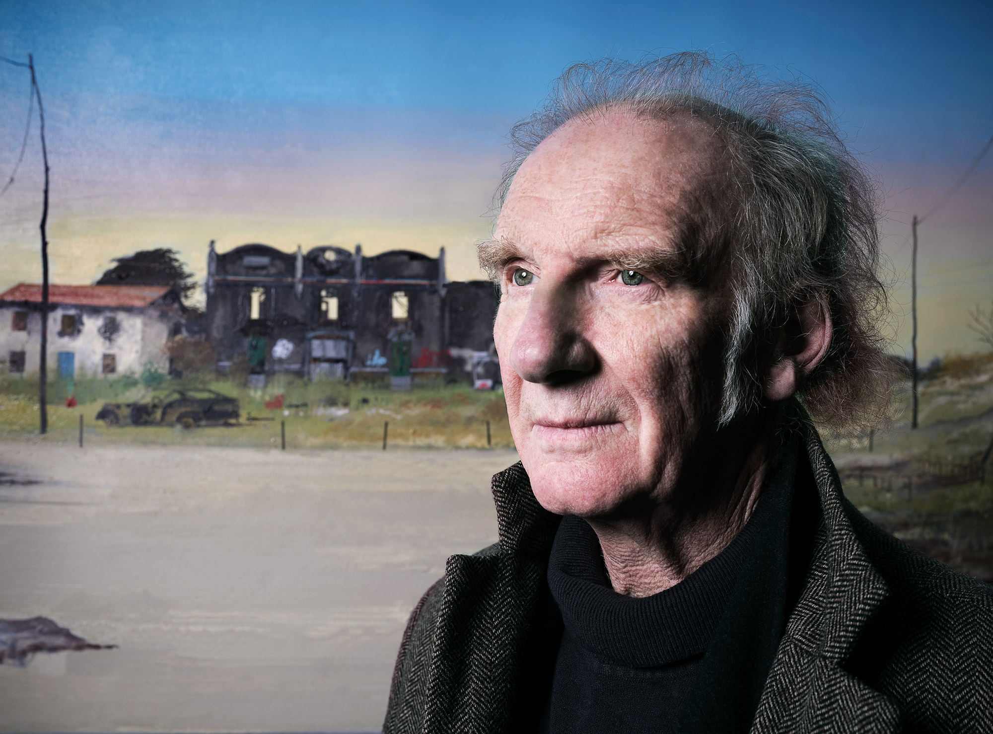 Colour portrait of  Jock McFadyen RA with a painting as a background, photo by Del Francis with a Fujifilm GFX 100S

