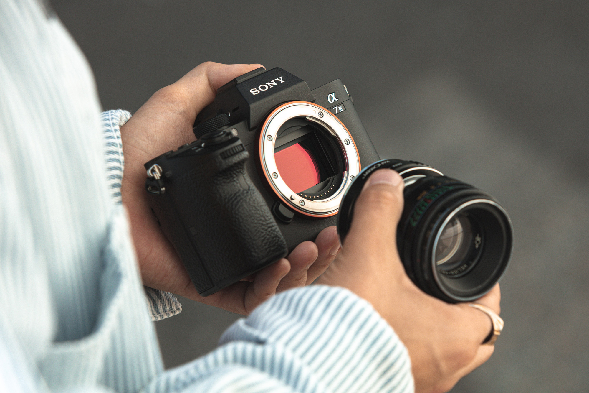 Une personne tient un objectif sur le Sony A7 III