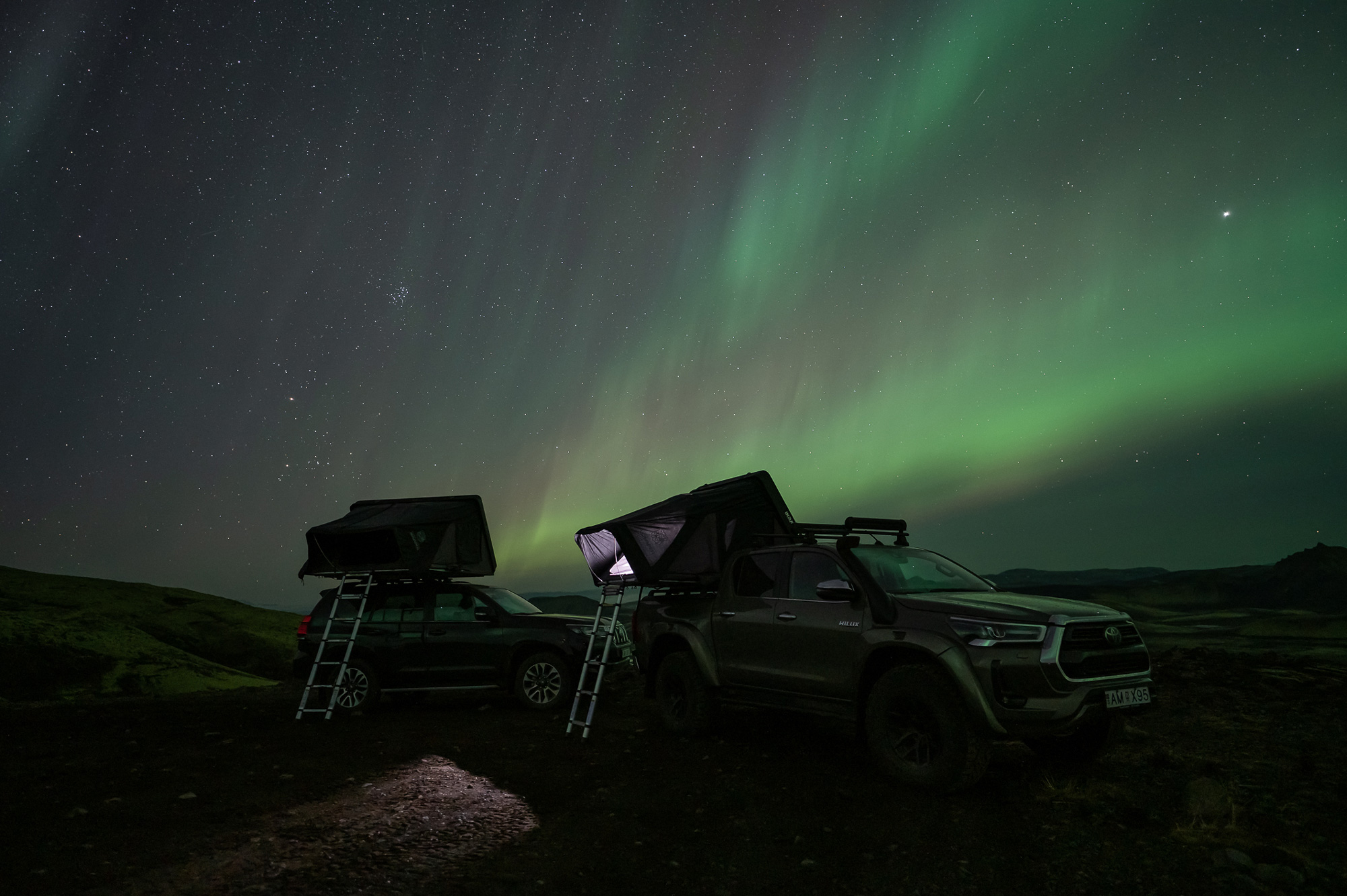 The northern lights appear over two parked cars covered in darkness in Iceland, shot by Paul Watson with a Nikon Z6