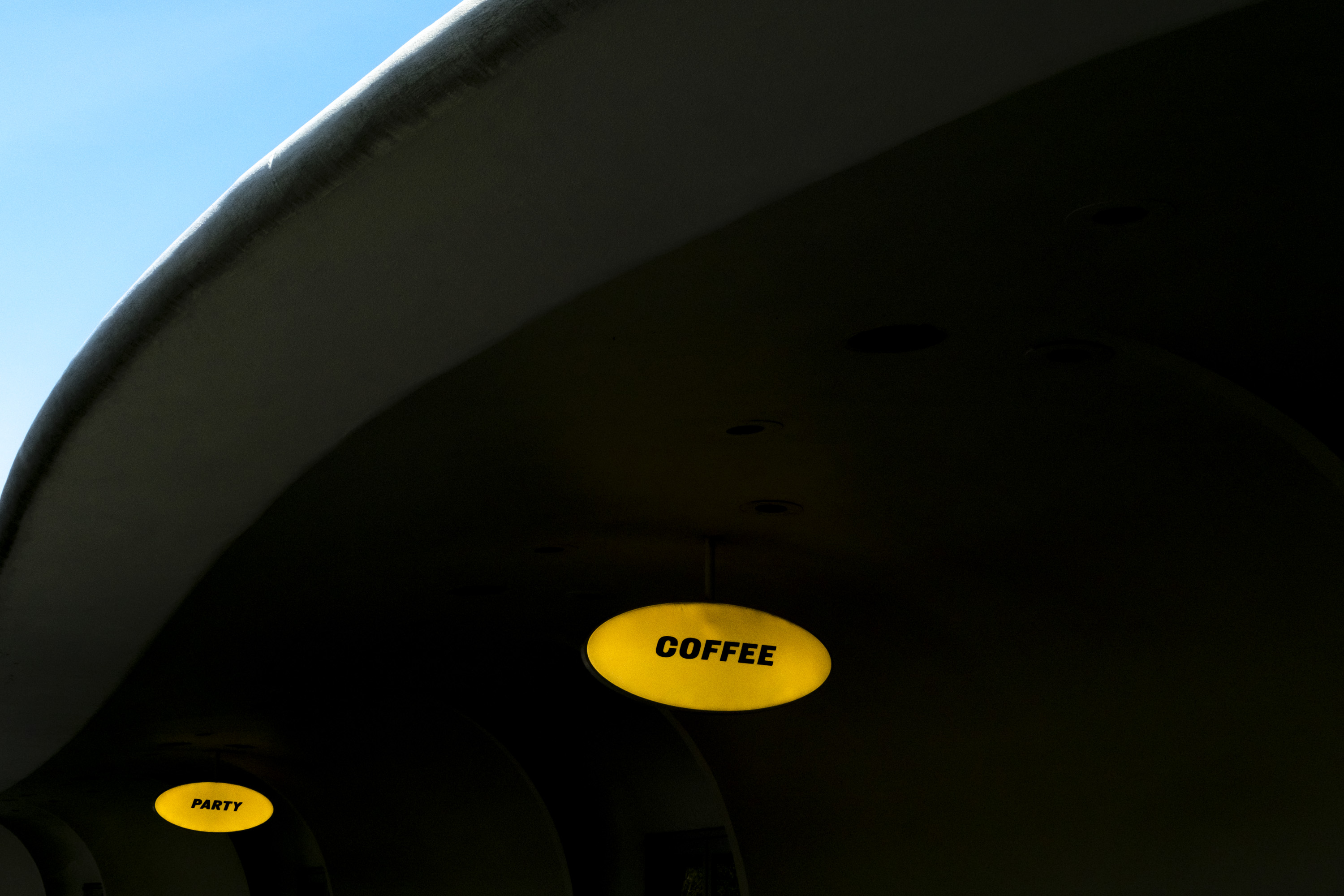 Two yellow signs, one says ‘Coffee’ and one says ‘Party’ at TWA Airport in New York. Shot on the X-Pro 3 by Ian Howorth.