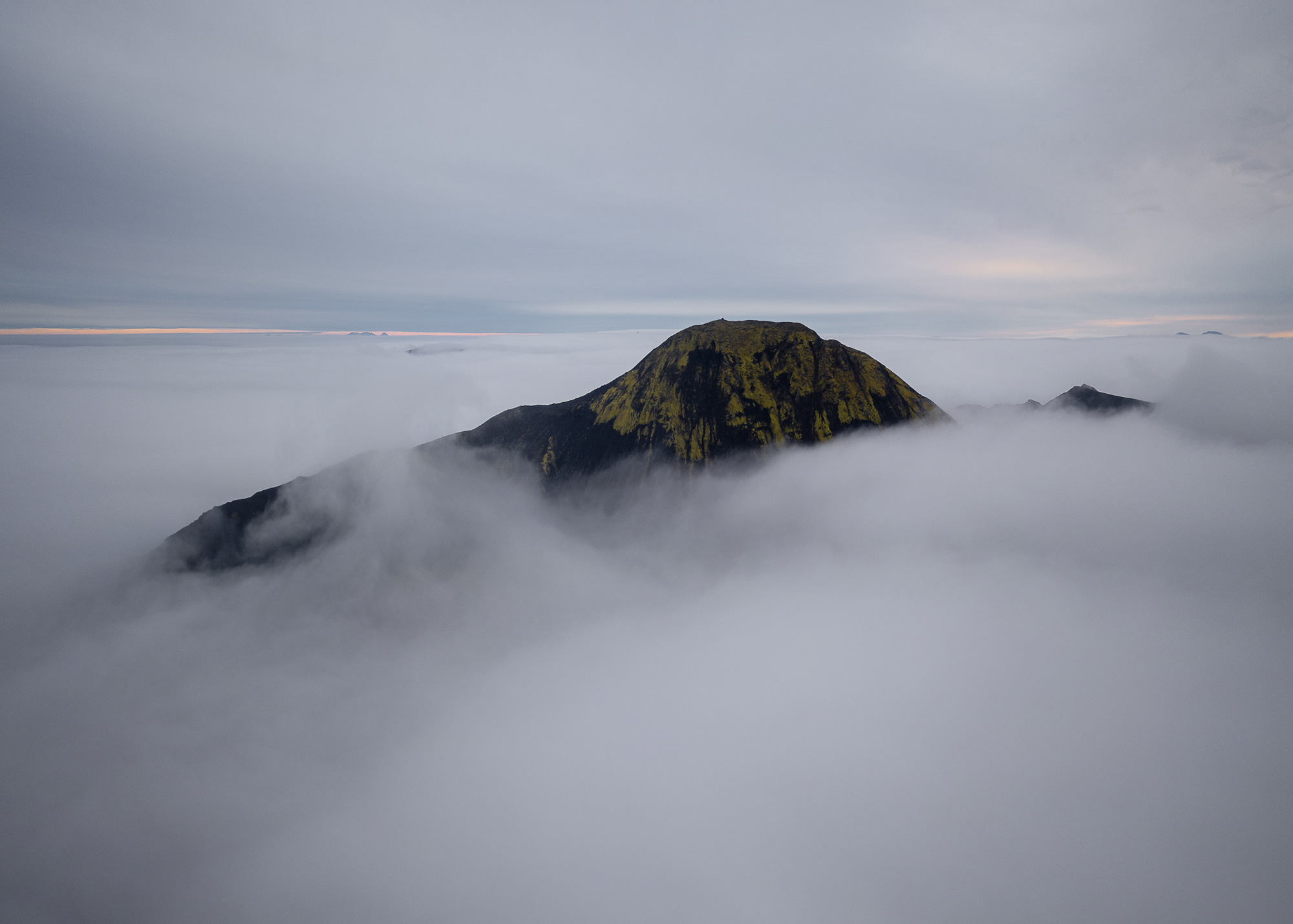 An aerial drone photo of a mountain peak bursting through cloud and fog in Iceland, shot by Paul Watson with a DJI Mavic 2 Pro