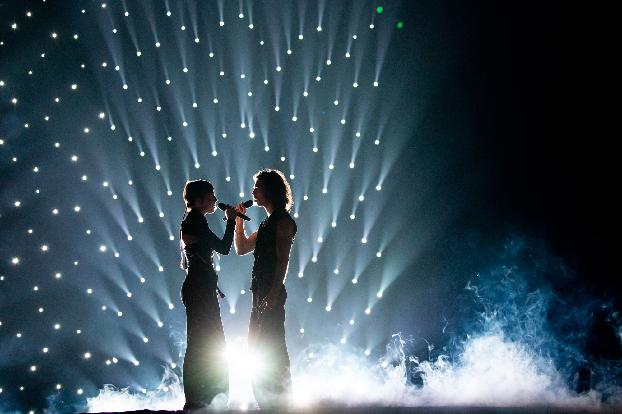 Eine Silhouette von zwei Künstler:innen auf der Bühne beim ESC 2023, mit Scheinwerfern und Rauch hinter ihnen auf der Bühne. Aufgenommen von Chloe Hashemi mit der Canon EOS 5D Mark IV.