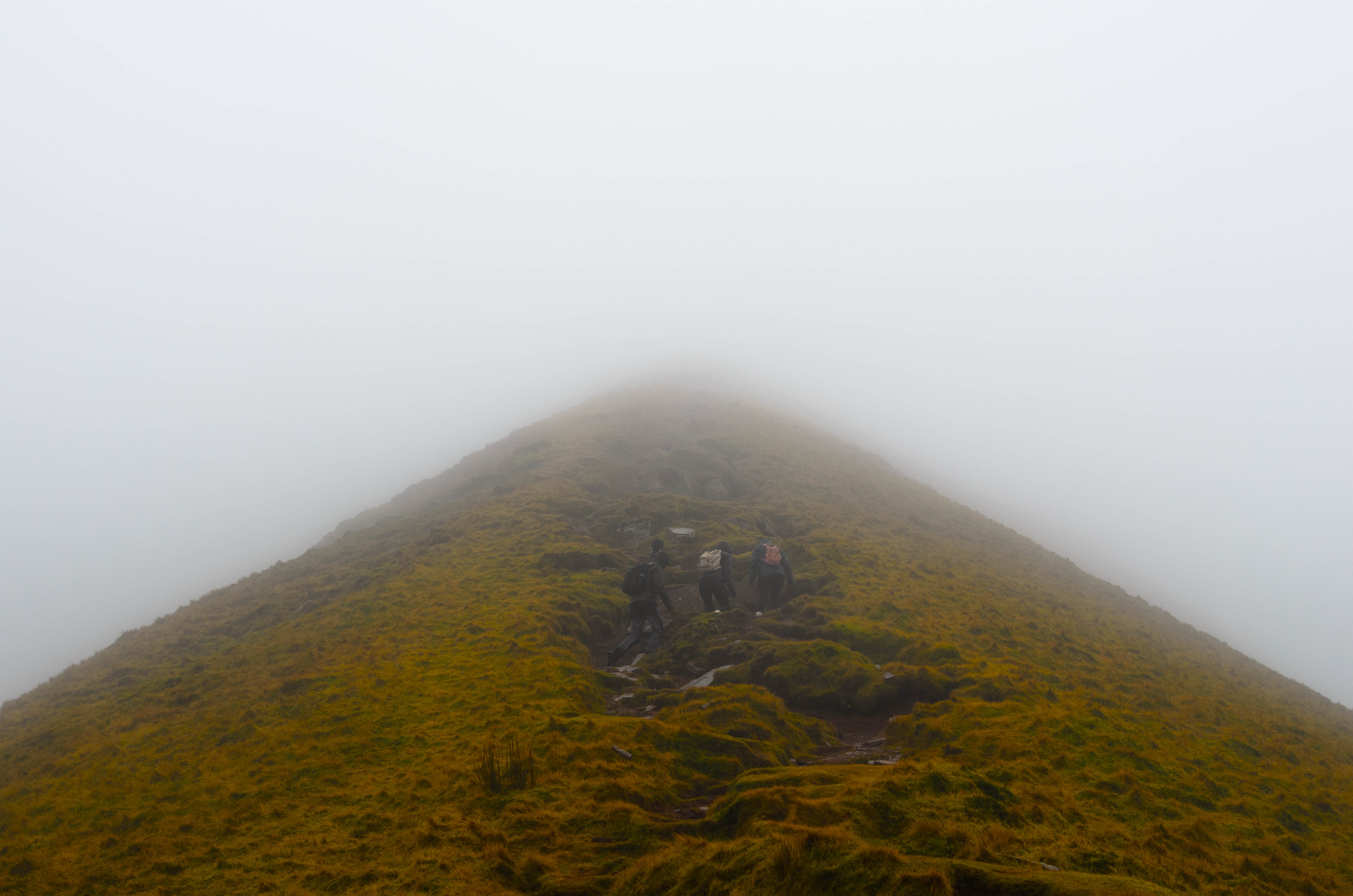 Drie mensen beklimmen een piek in de Brecon Beacons, Wales in mistige omstandigheden, gefotografeerd door Connor Redmond. 