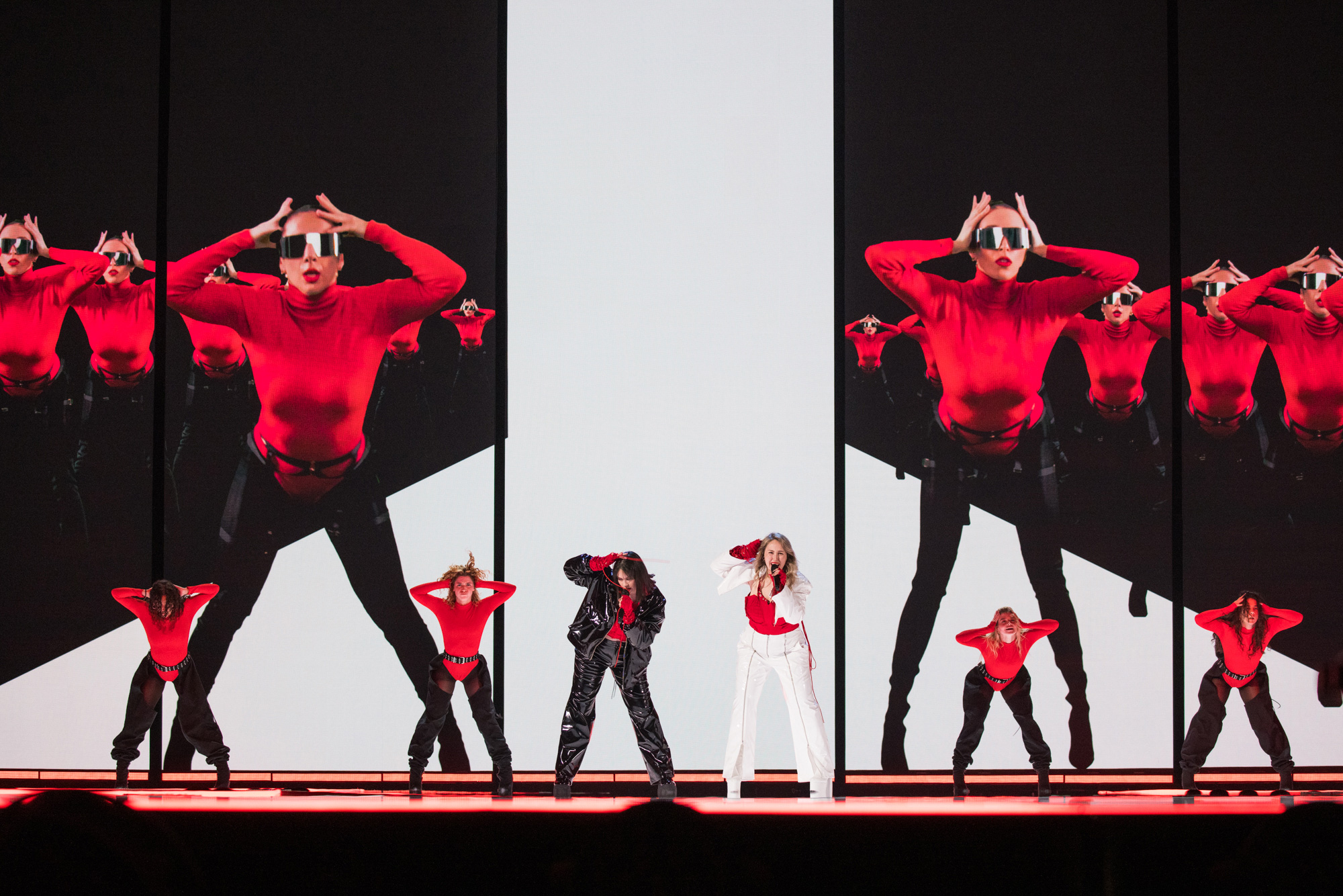 Sechs Darsteller:innen auf der Bühne des ESC 2023 in schwarzer, roter und weißer Kleidung, hinter ihnen große Bildschirme, auf denen Tänzer:innen in Rot und Schwarz zu sehen sind, aufgenommen von Corinna Cumming mit der Canon EOS R5.
