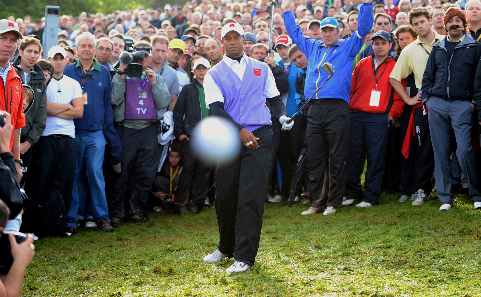 Tiger Woods looking directly at the camera with a blurred golf ball in front, presumably about to hit the camera