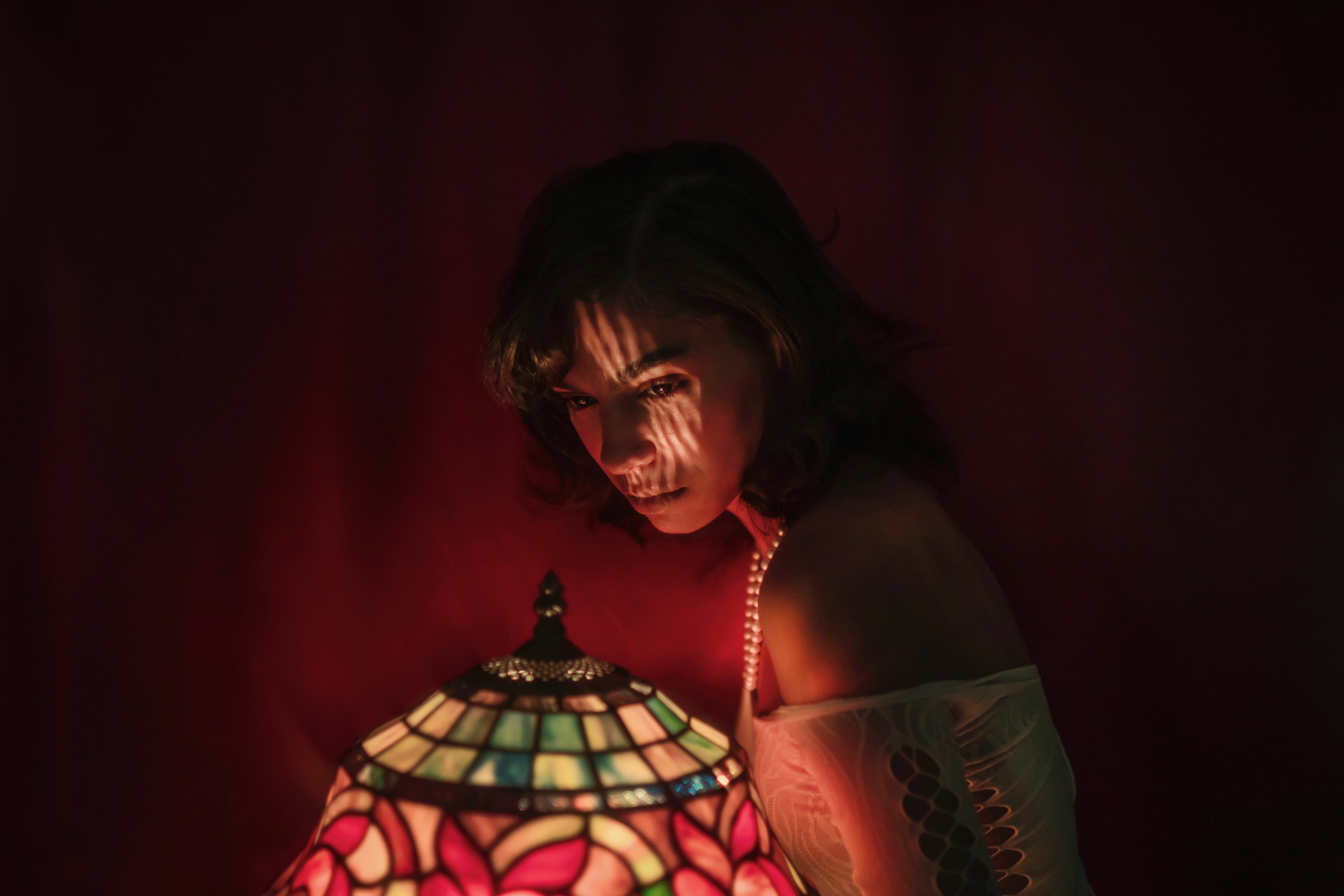 Person looking at stained glass lamp with light on face, photo by Brandon Woelfel