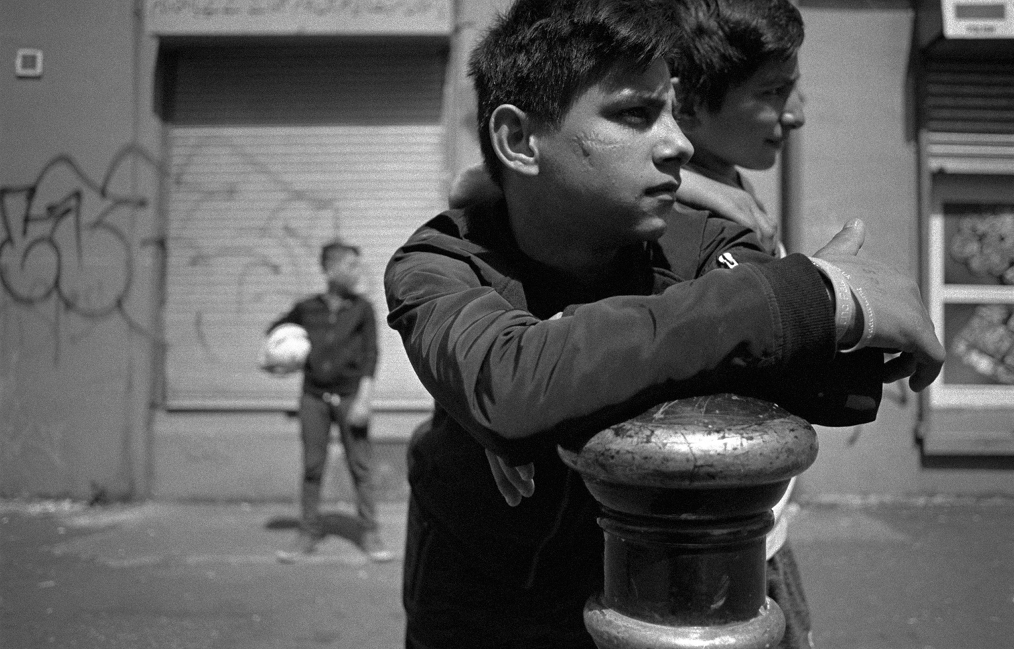 A black-and-white street portrait photo of kids who have been playing football in the street, image by Simon Murphy