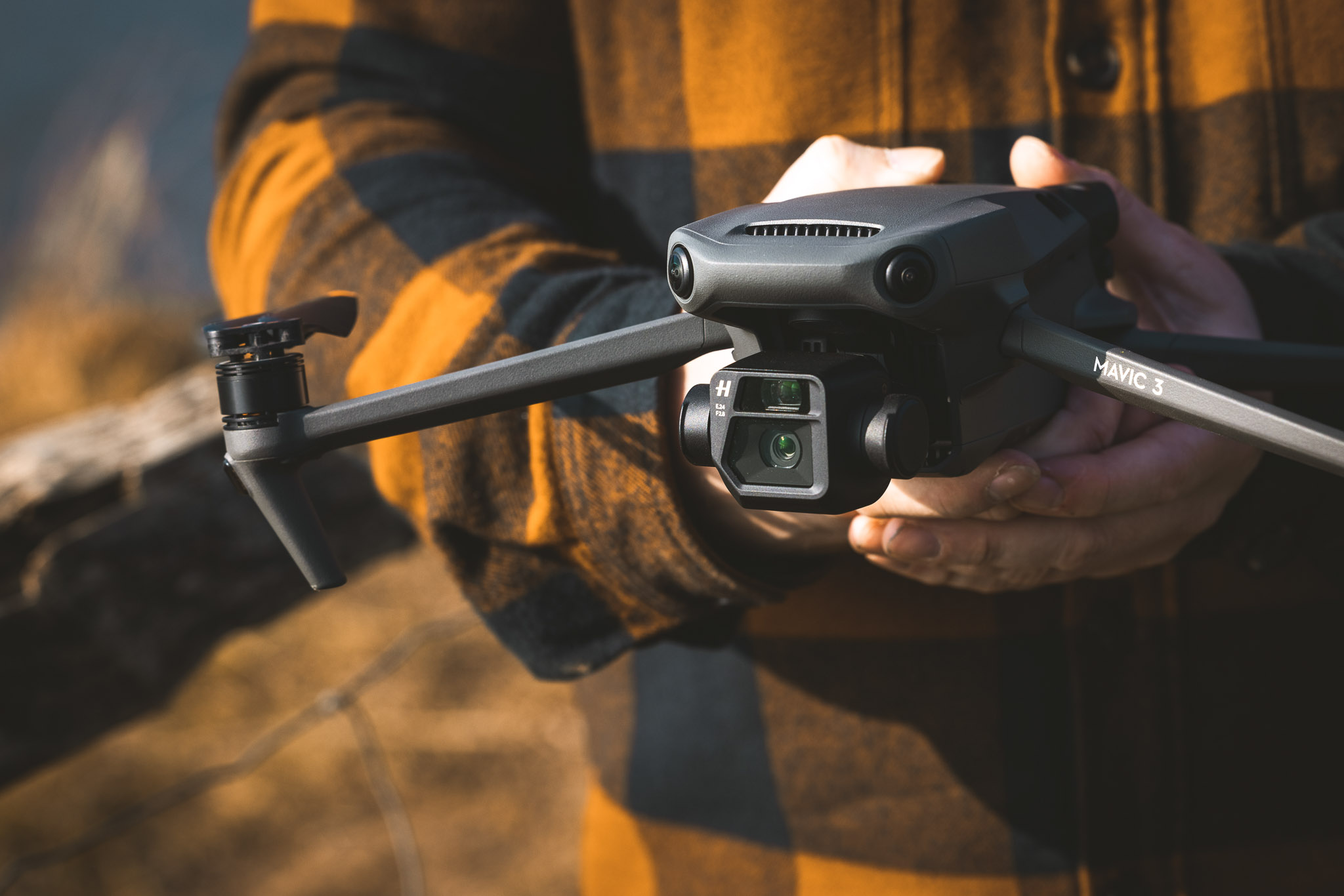Close-up of a DJI Mavic 3 drone being held by hand, highlighting the design and rear obstacle sensors.