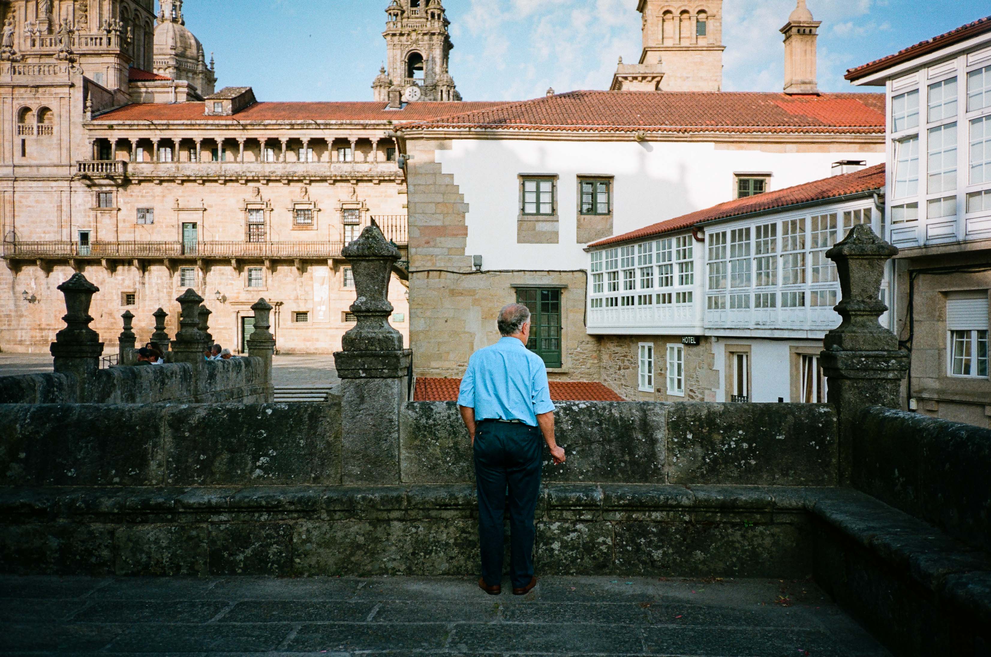 A person wearing a light blue shirt stares out into the distance longingly just off the Plaza del Obradoiro. By Connor Redmond.