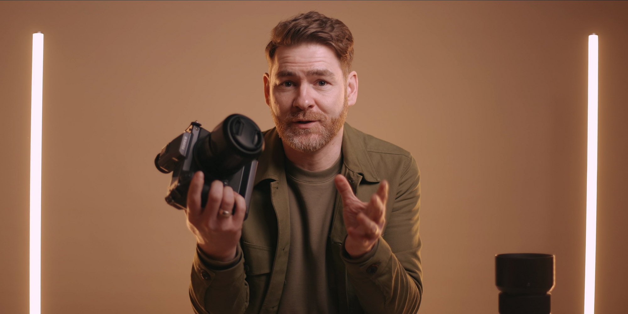A still from a video of portrait photographer Simon Murphy holding the Fujifilm GFX 100 and talking to the audience

