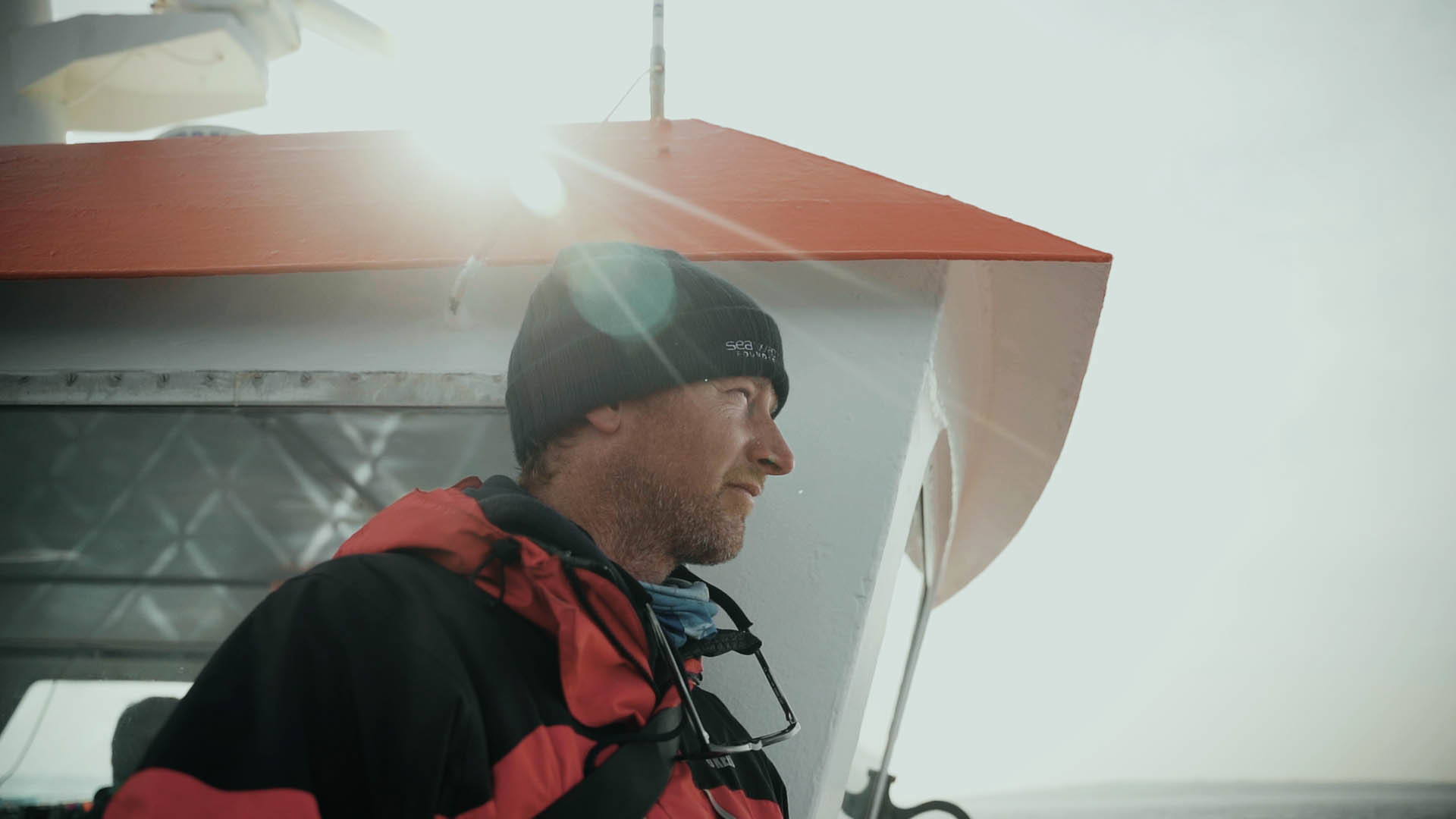 Steve Truluck met een rode en zwarte waterdichte jas en een hoed op een boot, een still uit de korte film Truluck van Matt Cannon en Jake Smallwood.
