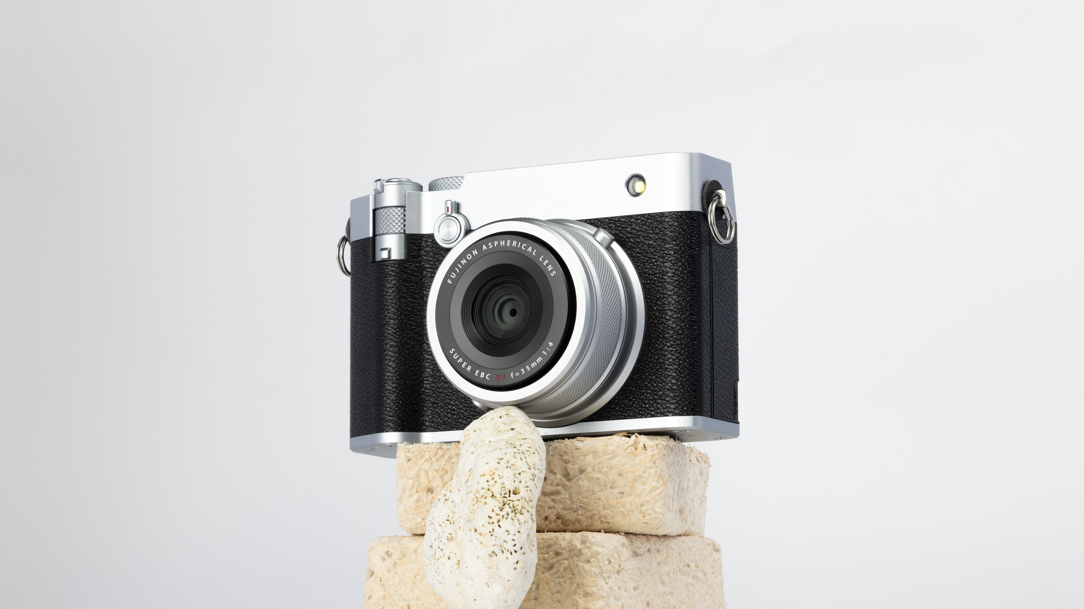 A product shot of a secondhand Fujifilm GFX100RF camera propped up on a rocky podium