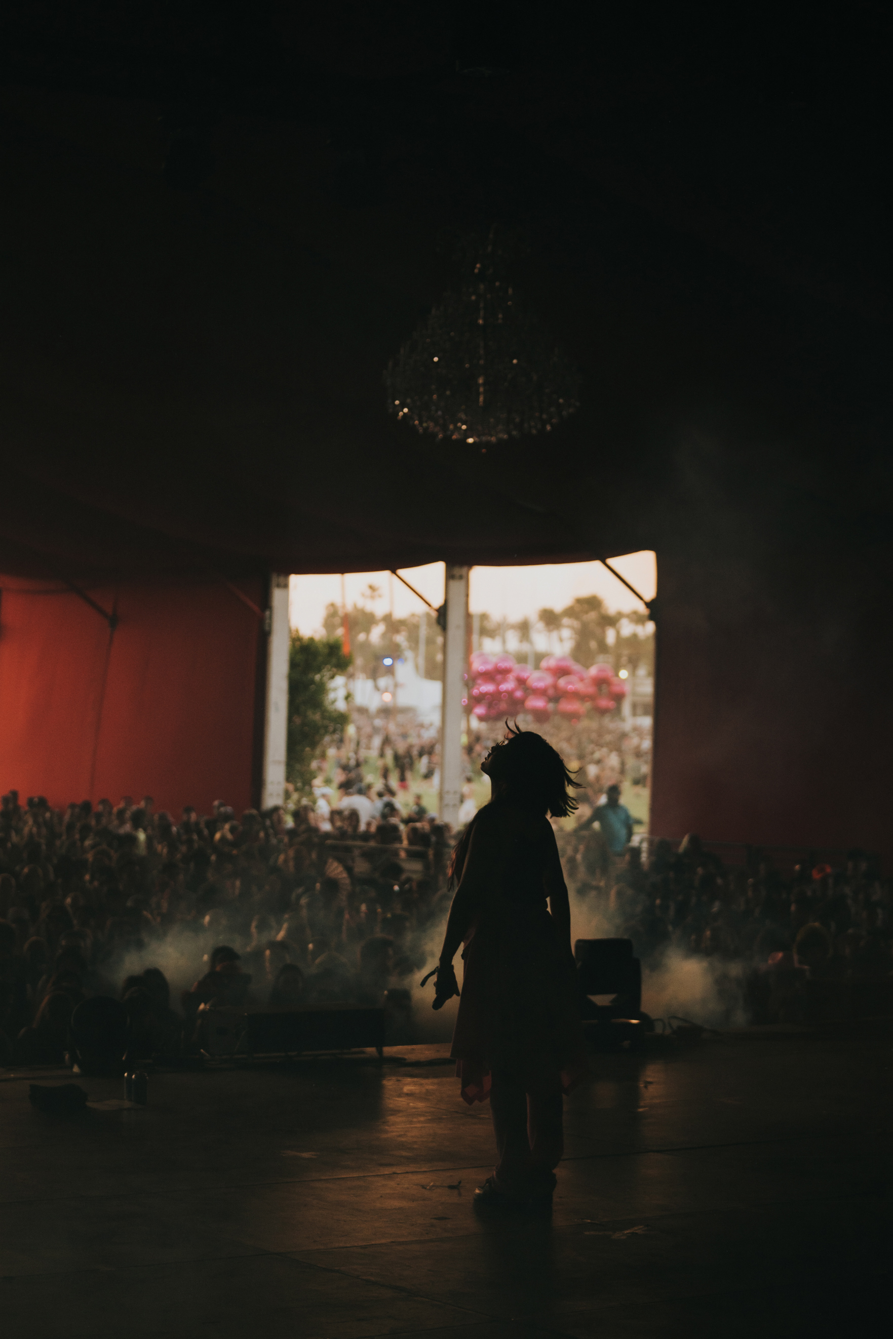 Silhouette of artist Yaeji during golden hour performance at Coachella Music Festival 2023 on stage with crowd in the background.