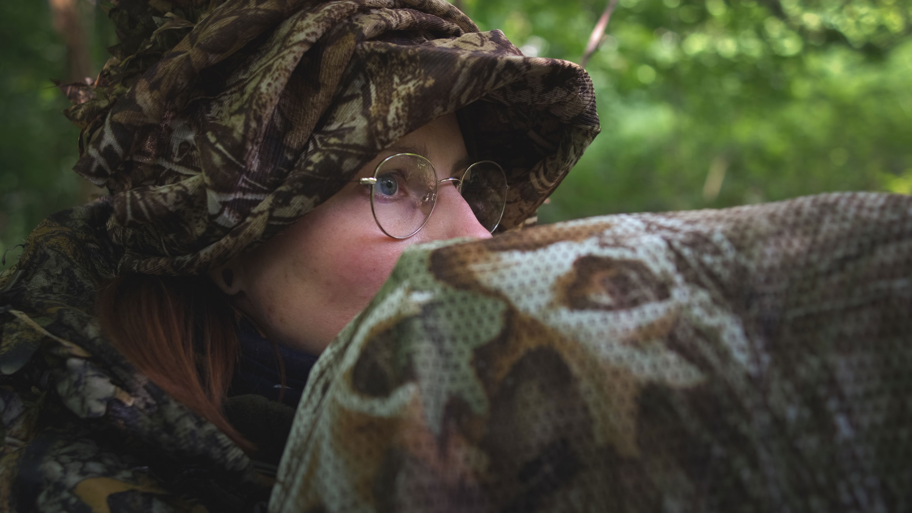 Person im Wald in Camouflage gekleidet, von der Seite fotografiert