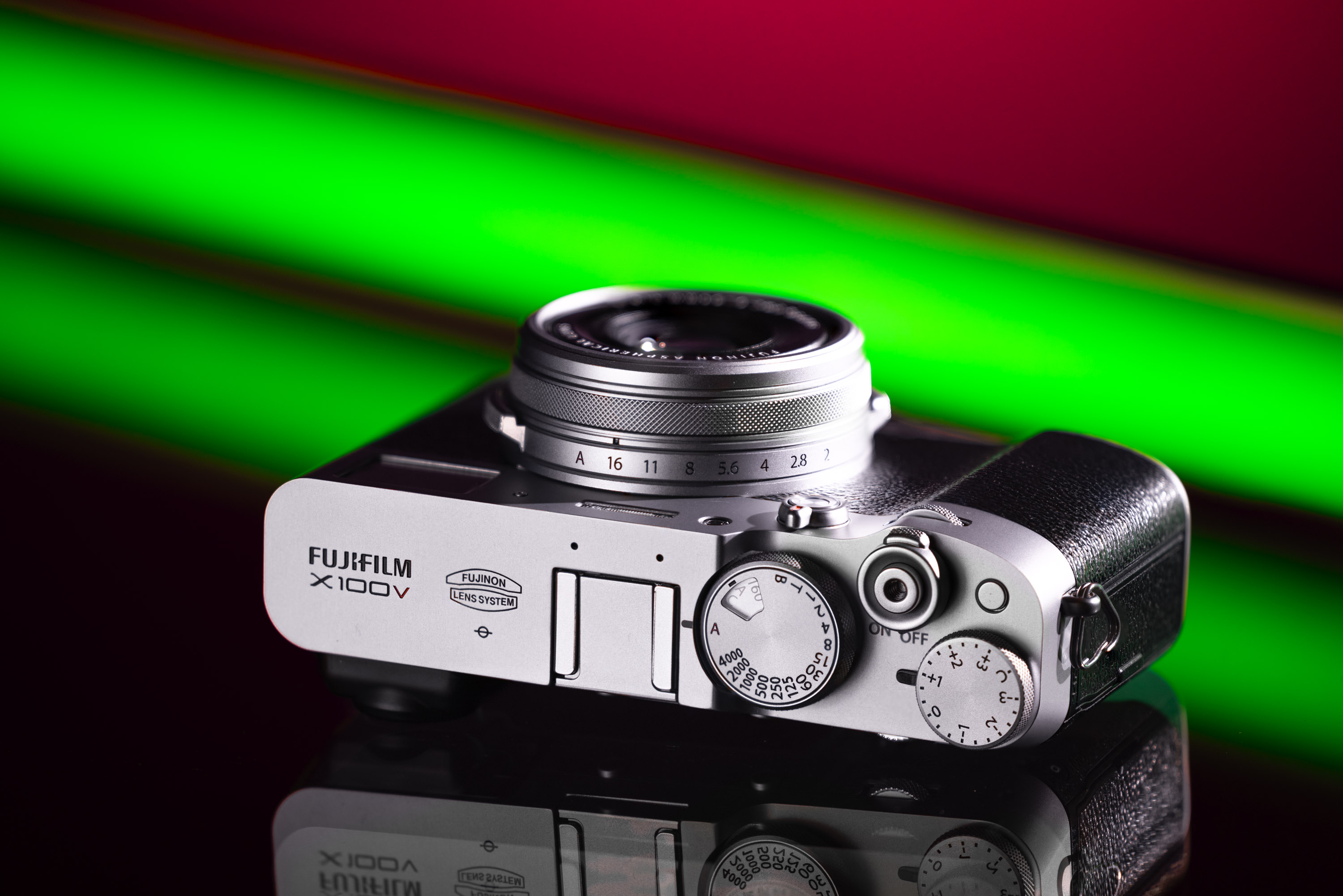 Tweedehands Fujifilm X100V op een felgroene en kastanjebruine achtergrond