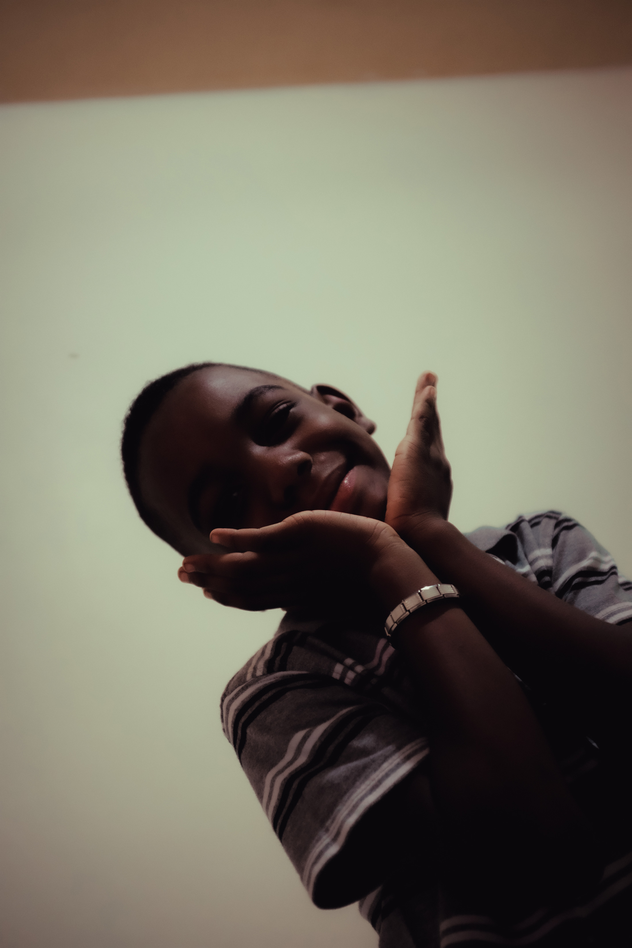 A portrait of a young person smiling at the camera with his hands on his face