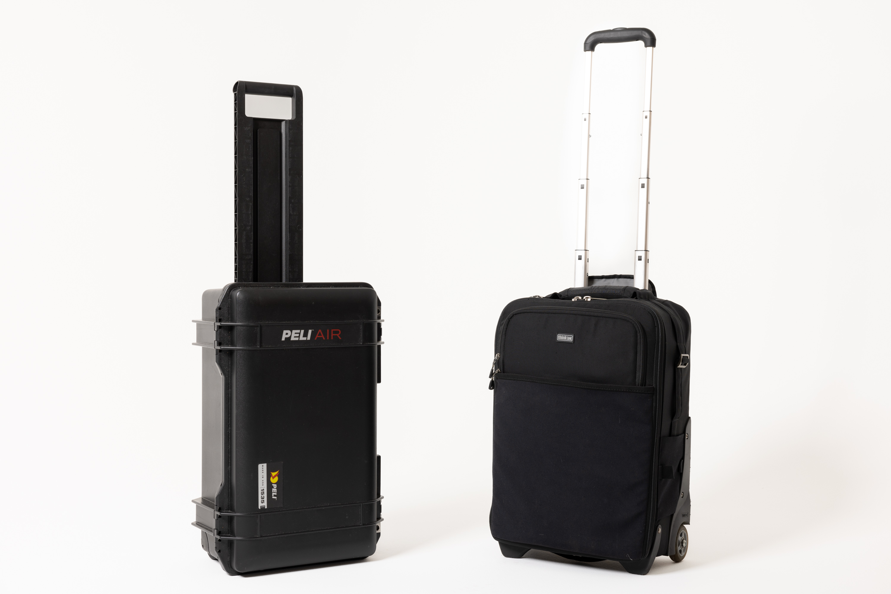 Een Peli 1535 Air Case fotografie hardcase en een ThinkTank Airport International V2.0 fotografie softcase naast elkaar tegen een witte achtergrond.