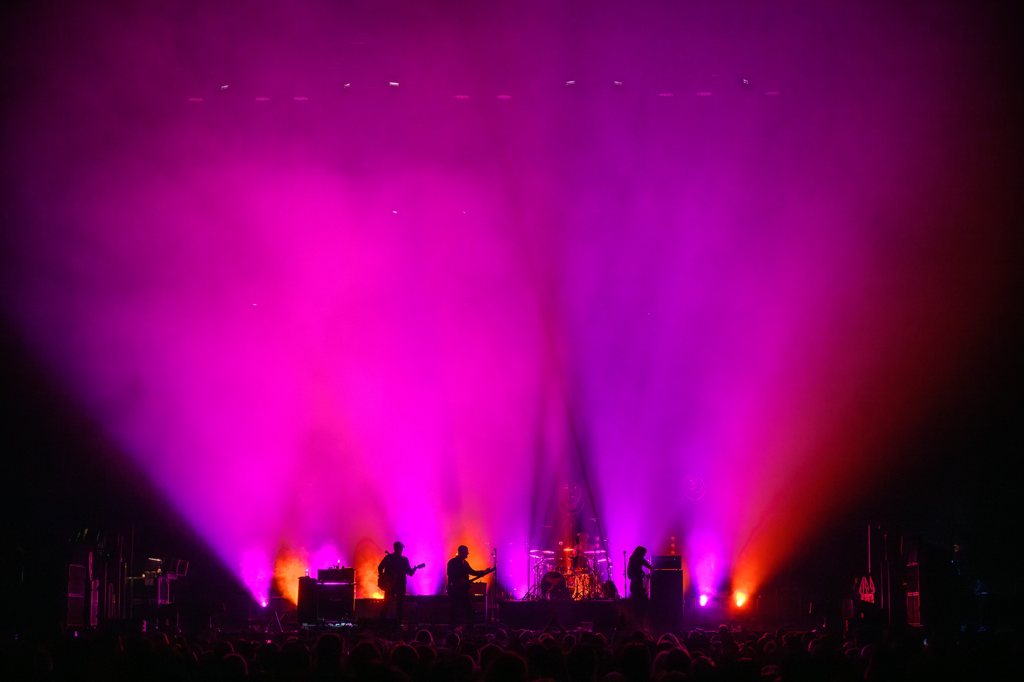 Wide image of The Pixies on stage with pink lights at a music festival. Image taken by James Joiner on a Nikon Z9.