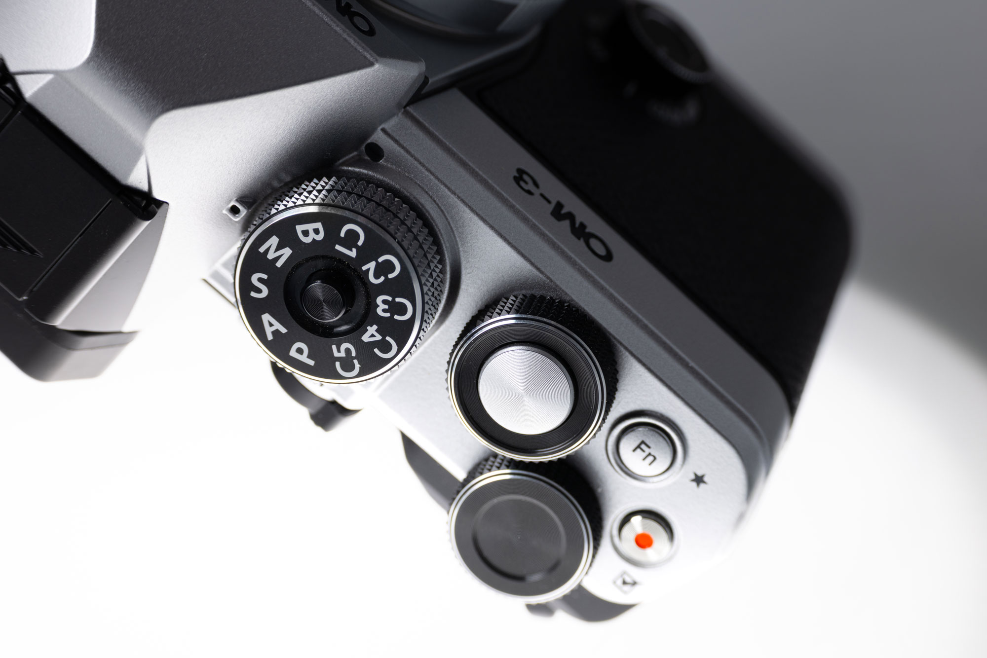 A close-up of a dial on a used OM System OM-3 camera